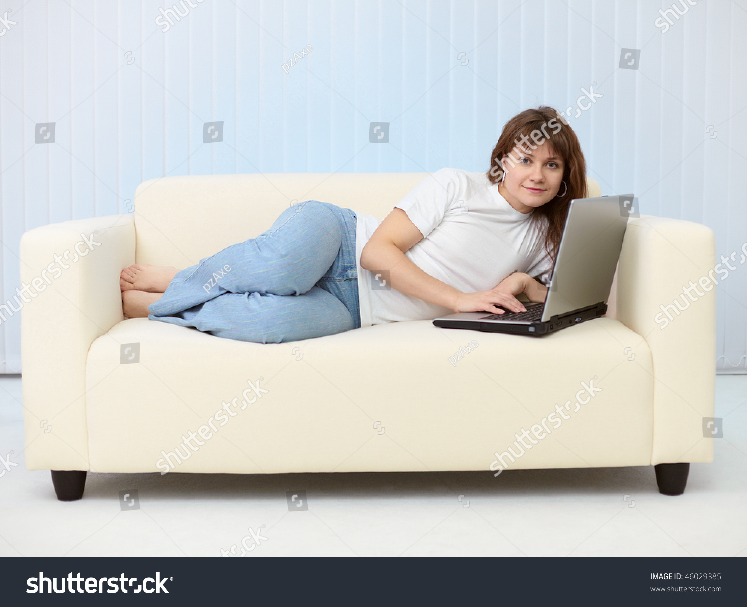 Девушка лежит на диване с ноутбуком