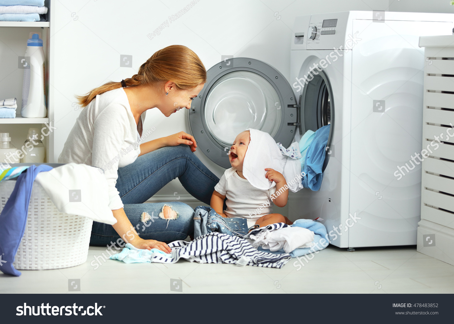 Stock Photo Mother A Housewife With A Baby Engaged In Laundry Fold Clothes Into The Washing Machine 478483852 