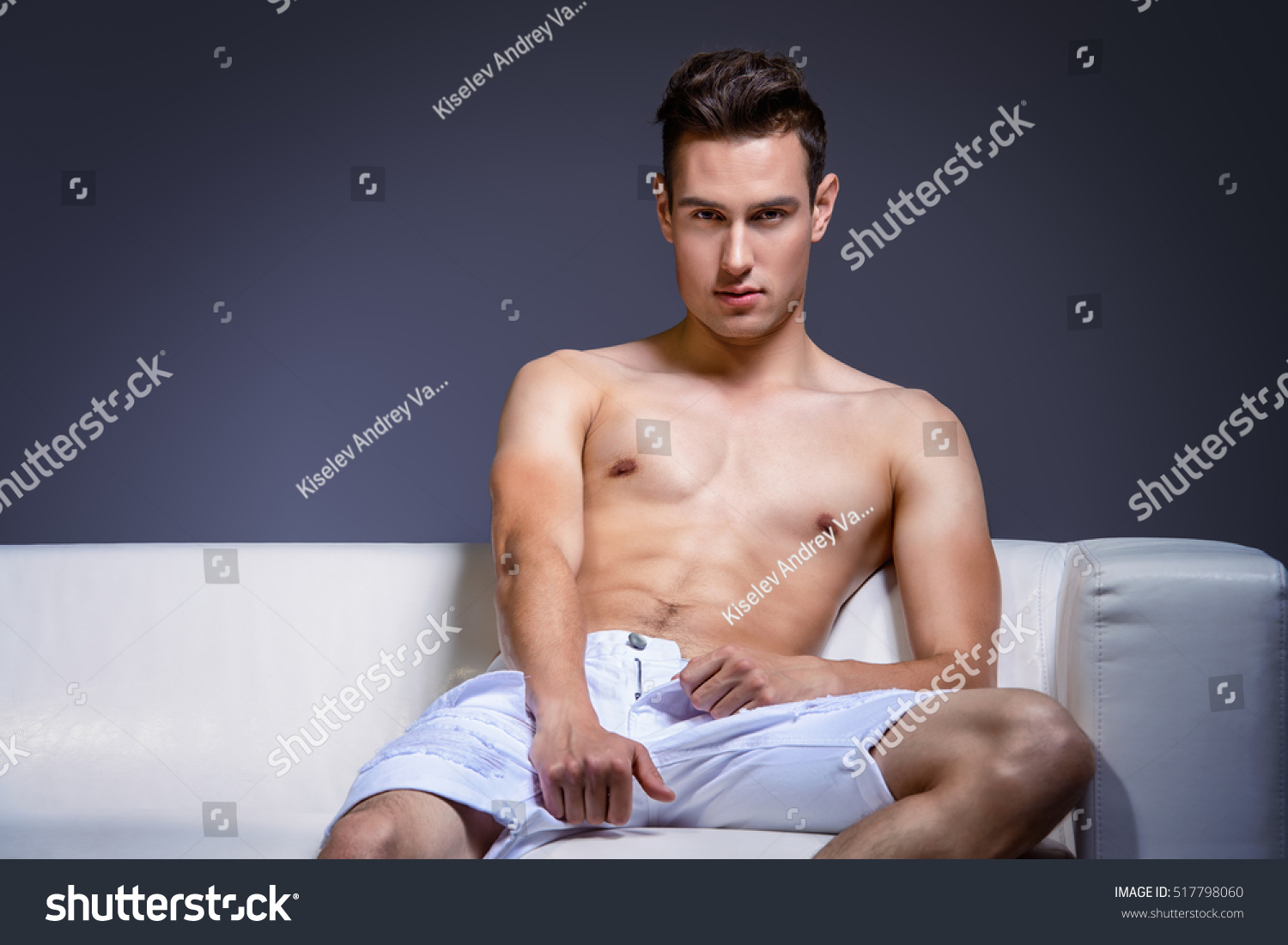 Handsome Shirtless Man Sitting On Couch Stock Photo