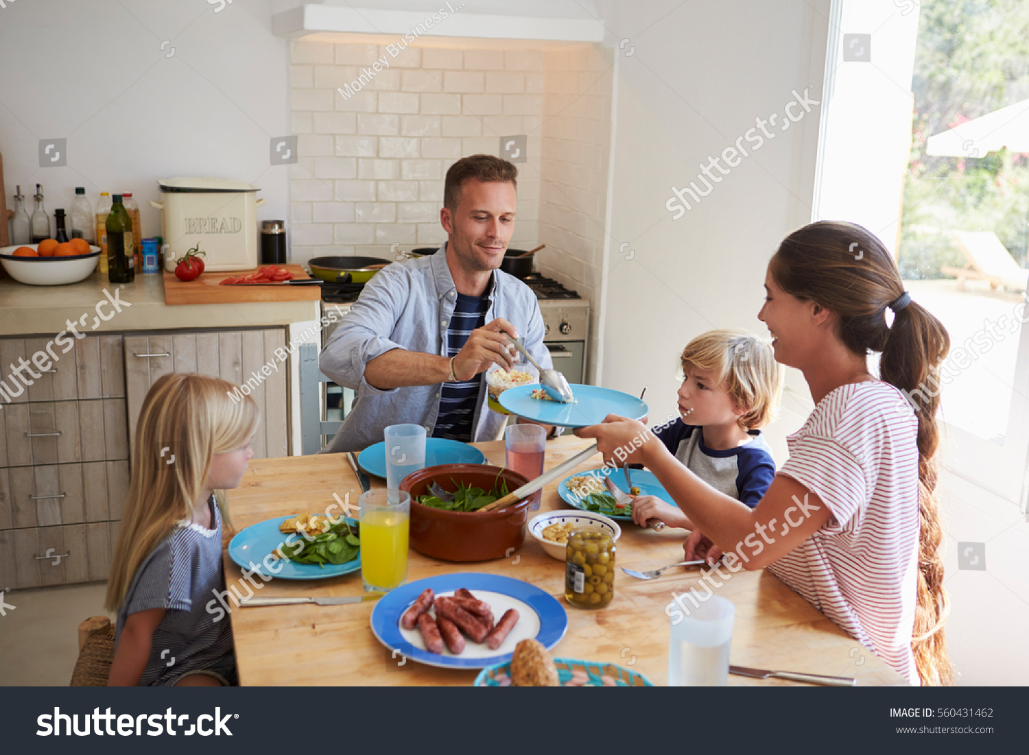 Stock Photo Family Sitting Around Kitchen Table Serving Lunch 560431462 