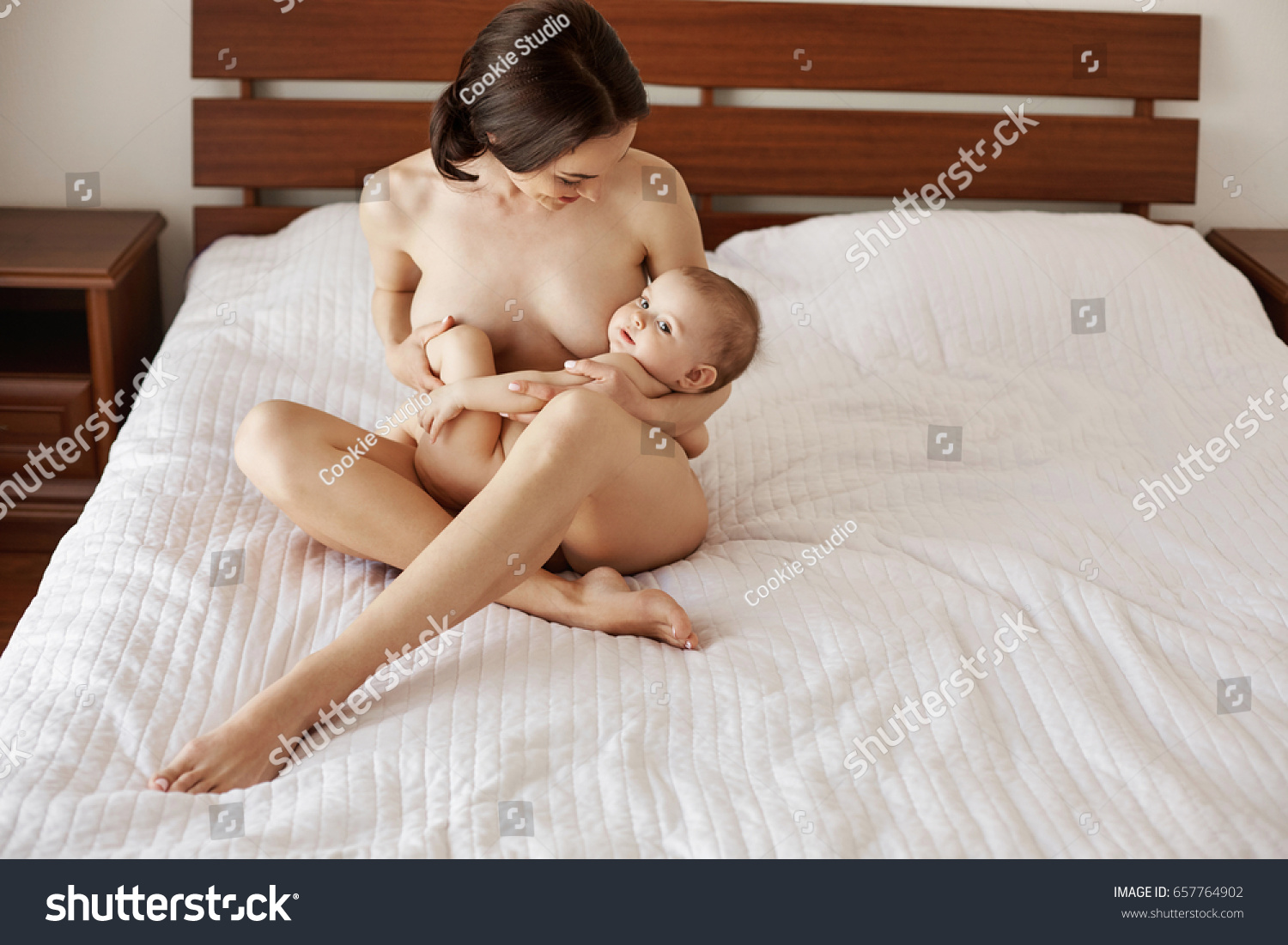 Стоковая фотография 657764902: Young Attractive Nude Mom Breastfeeding Hugg...