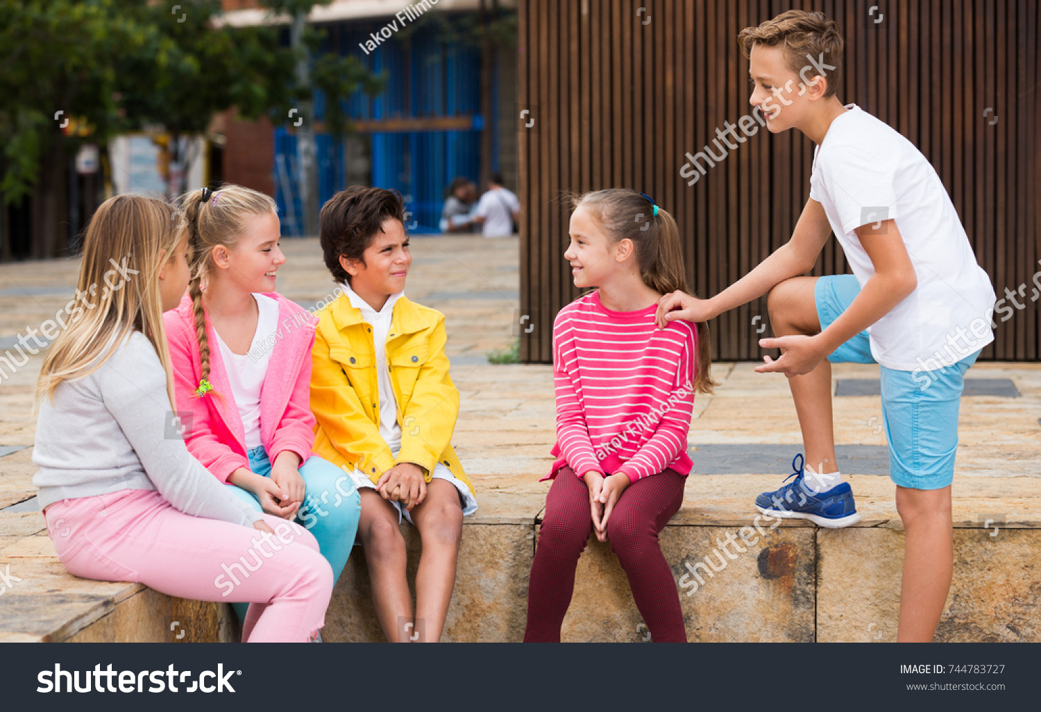 2 boys 3 girls. Two boys are talking. Children are talking. Five students three boys and two girls talking.