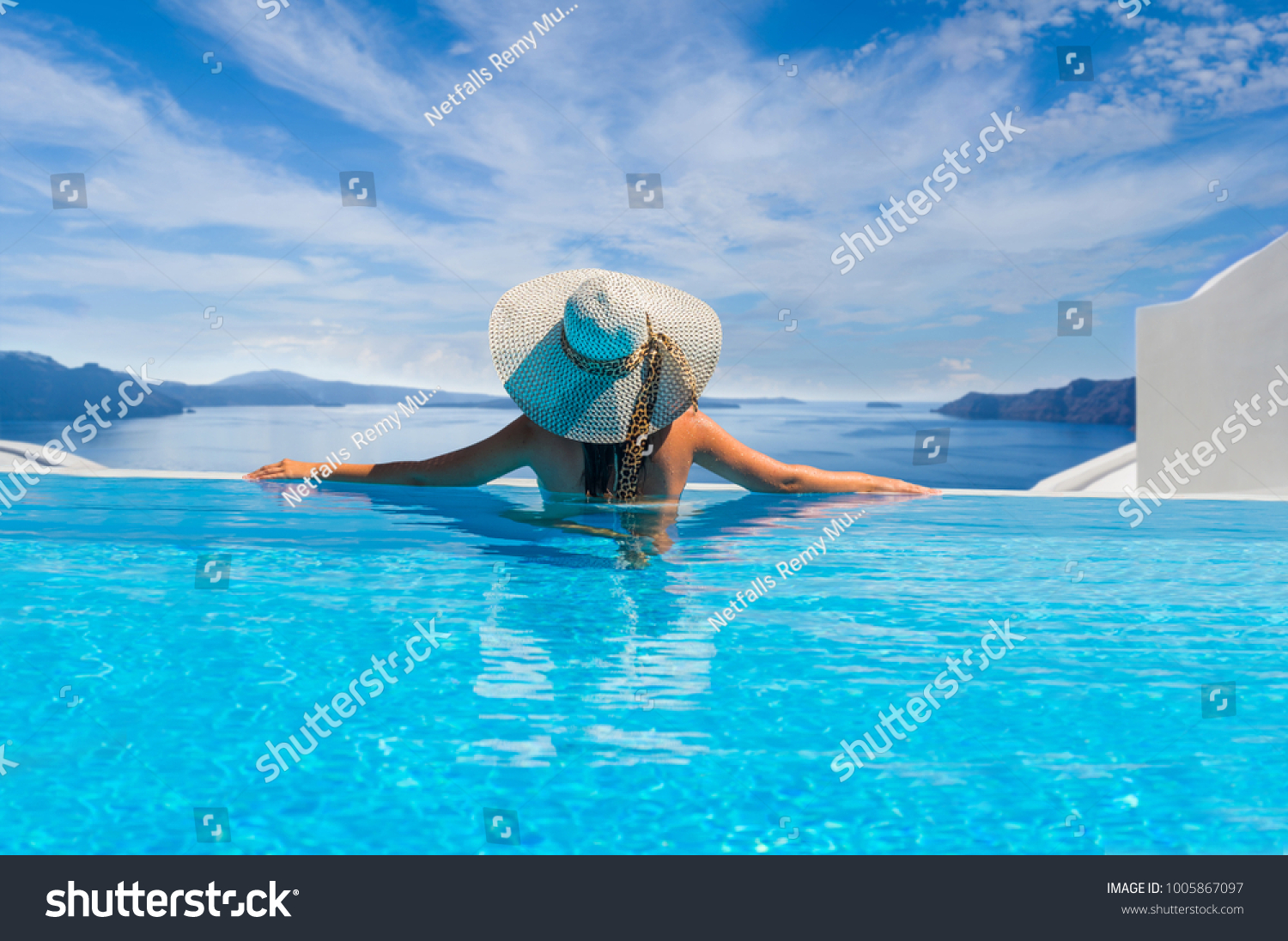 Woman enjoying relaxation in pool and looking at the view in Santorini Greece #1005867097