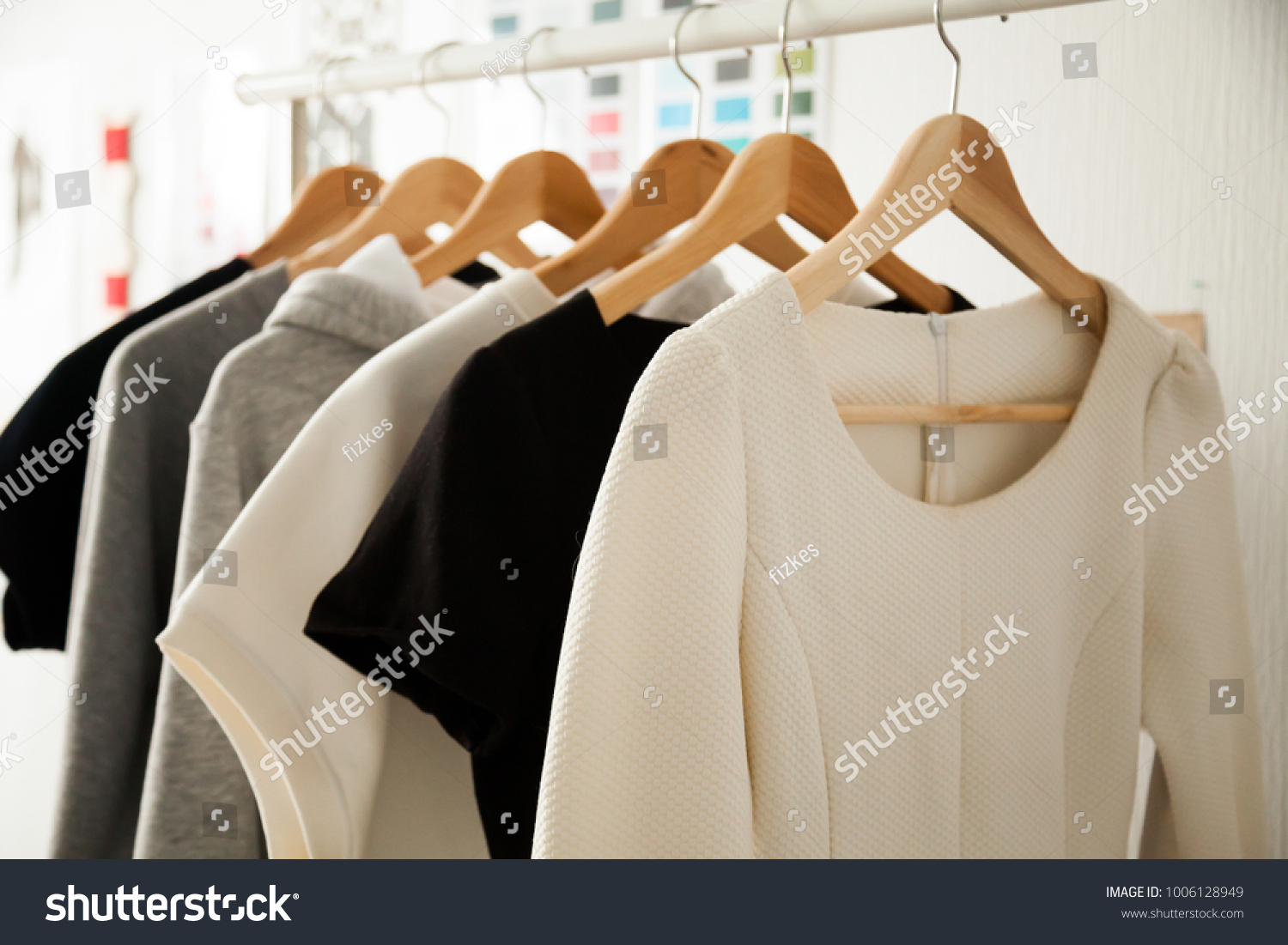 Women dresses new collection of stylish clothes wear hanging on hangers clothing rack rails, fabric samples at background, fashion design studio store concept, dressmaking tailoring sewing workshop #1006128949