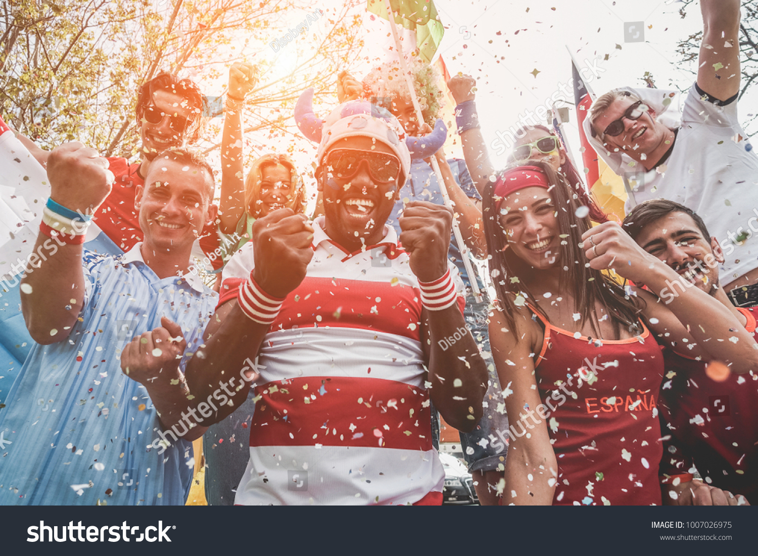 Multinational football supporters celebrating the begin of world competition - Happy multiracial people having fun together outside of stadium - Main focus on black man - Sport and bonding concept #1007026975