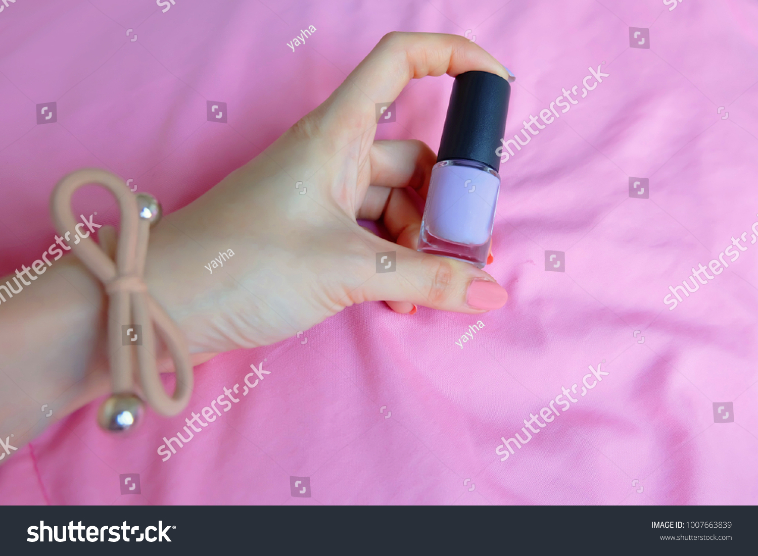 Pink Painted Nails. Beautiful Pink Nail Manicure with Pink Bottle in Woman is Hand on Pink Background Great for Any Use. #1007663839