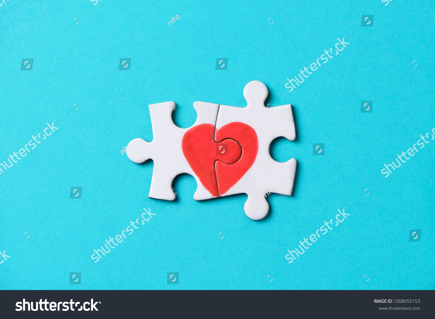 closeup of two pieces of a puzzle forming a heart, depicting the idea that love is a matter of two, on a blue background, with some blank space around it #1008055153