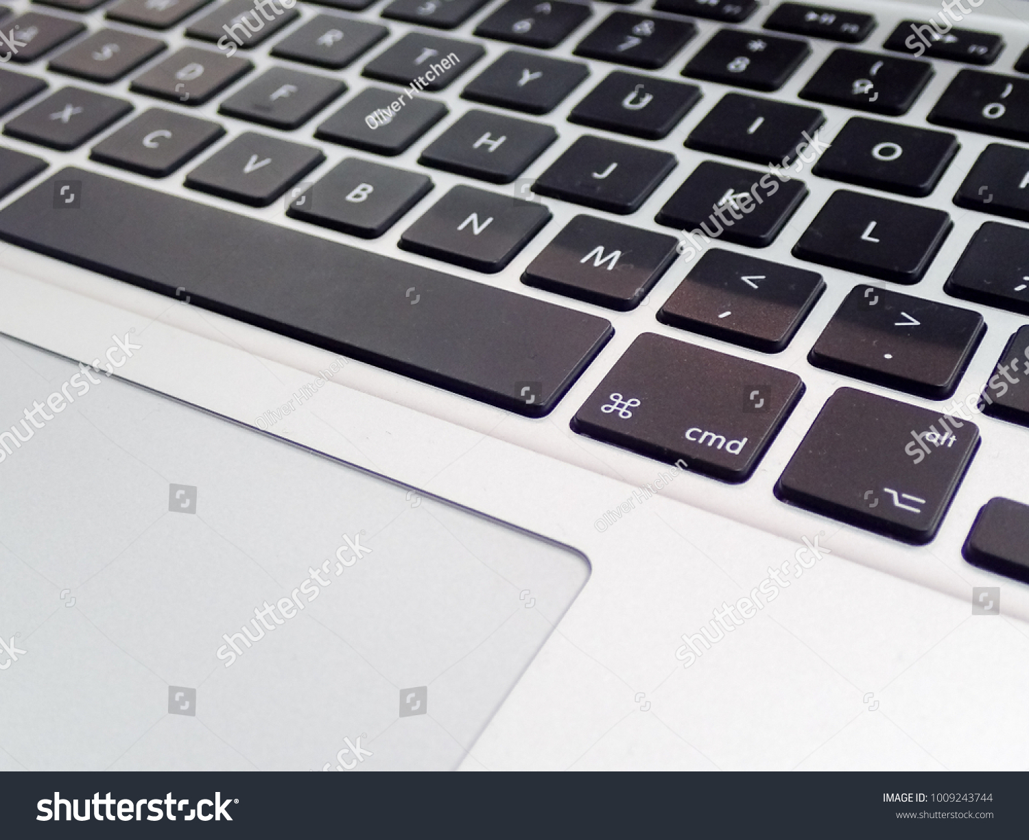 A modern, stylish computer keyboard, with the focus on the “cmd” and “alt” keys. The flat trackpad can be seen in the frame #1009243744