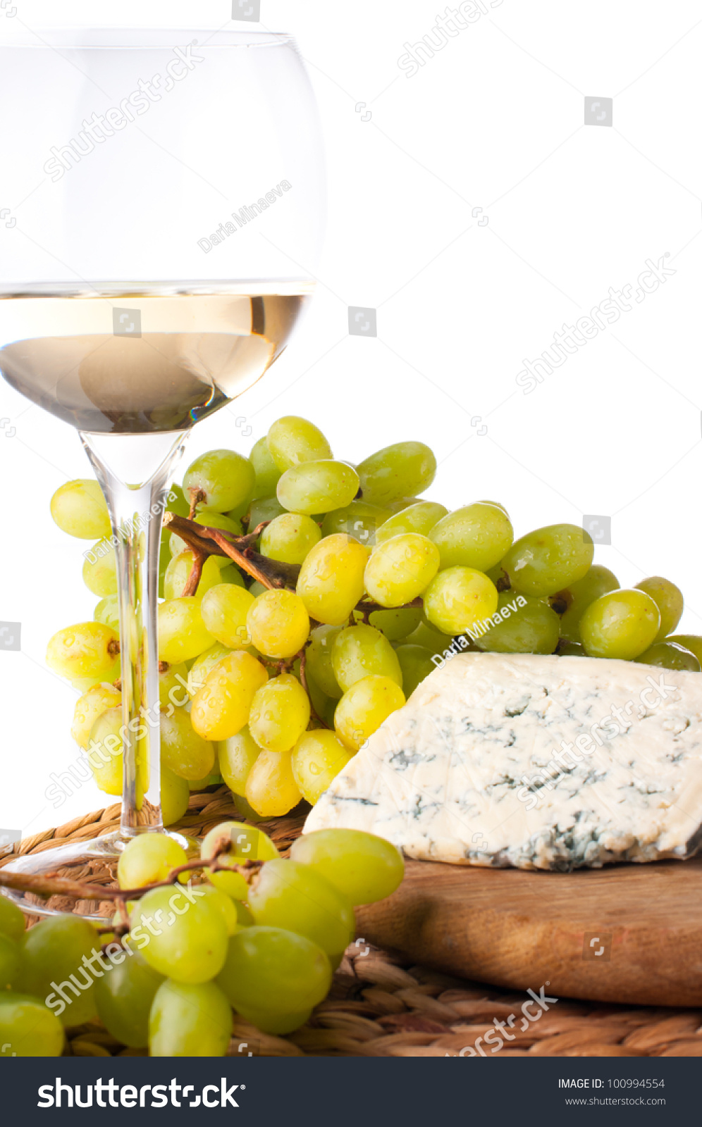 glass of white wine, blue cheese and a bunch of white grapes on white background #100994554