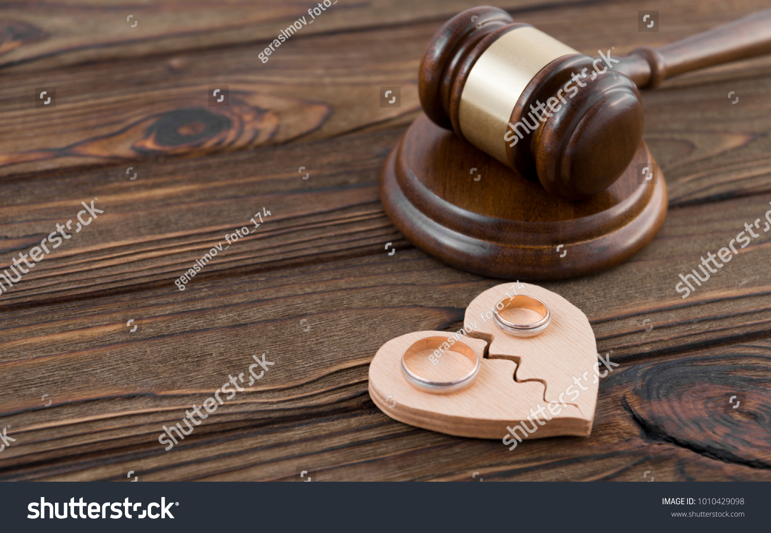 Wedding rings on the figure of a broken heart from a tree, hammer of a judge on a wooden background. Divorce divorce proceedings #1010429098