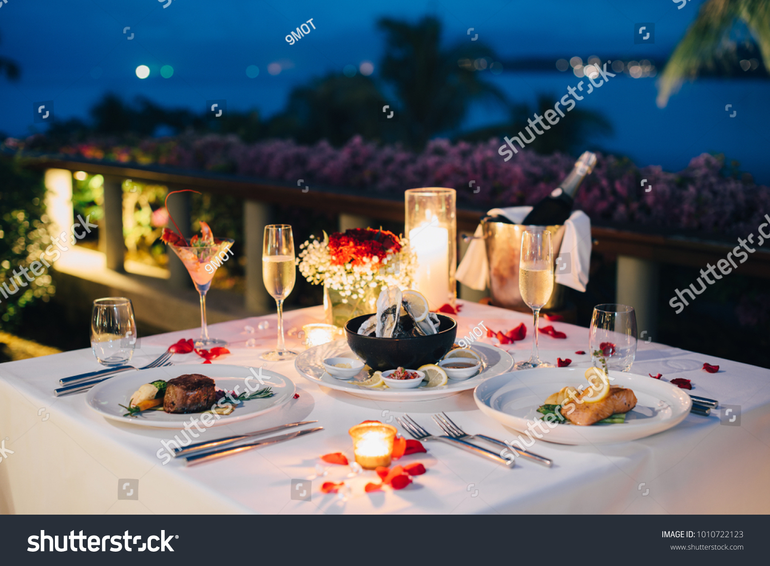 Luxury romantic candlelight dinner table setup for couple in ocean view restaurant on Valentine's day with Champaign & wine glasses and beautiful food decoration.   #1010722123