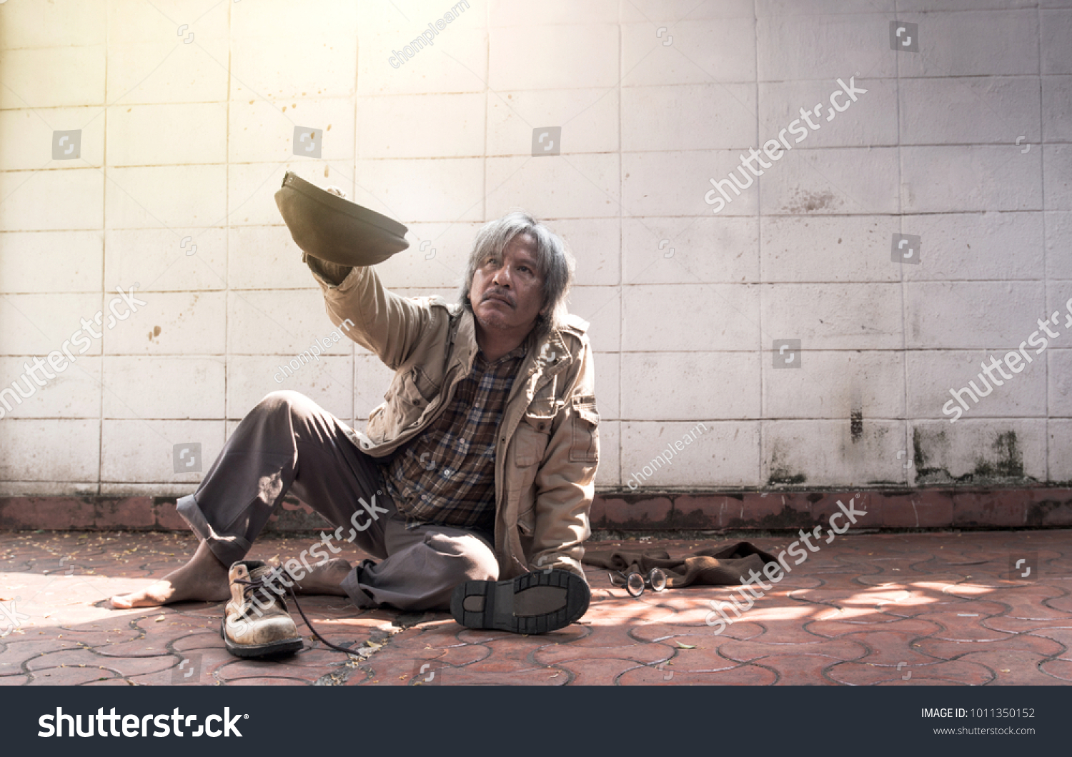 homeless and hungry vagrant holding a cup, asking for money and food #1011350152