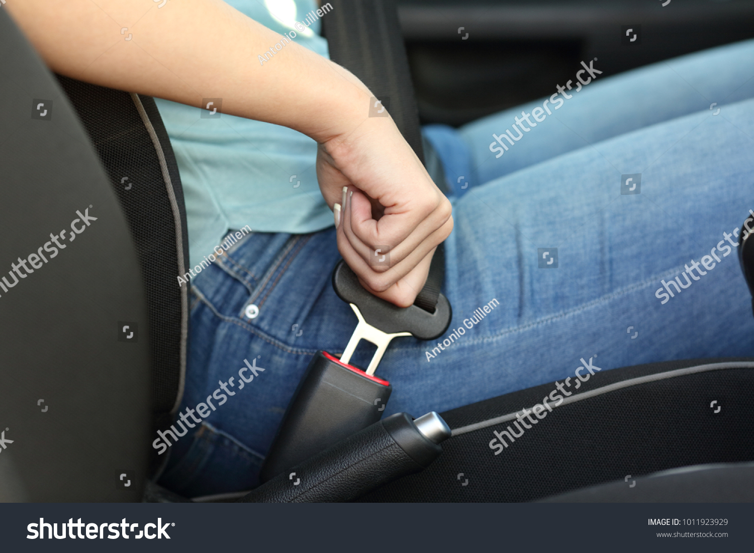 Close up portrait of a driver hand fastening seatbelt in a car #1011923929