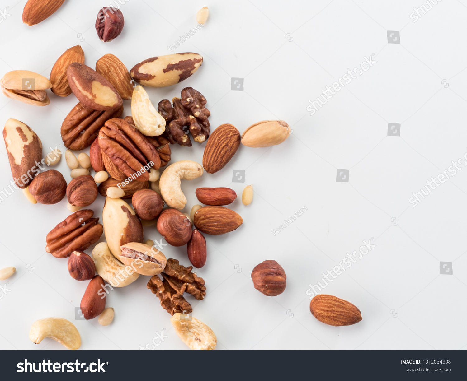 Background of nuts - pecan, macadamia, brazil nut, walnut, almonds, hazelnuts, pistachios, cashews, peanuts, pine nuts - with copy space. Isolated one edge. Top view or flat lay #1012034308