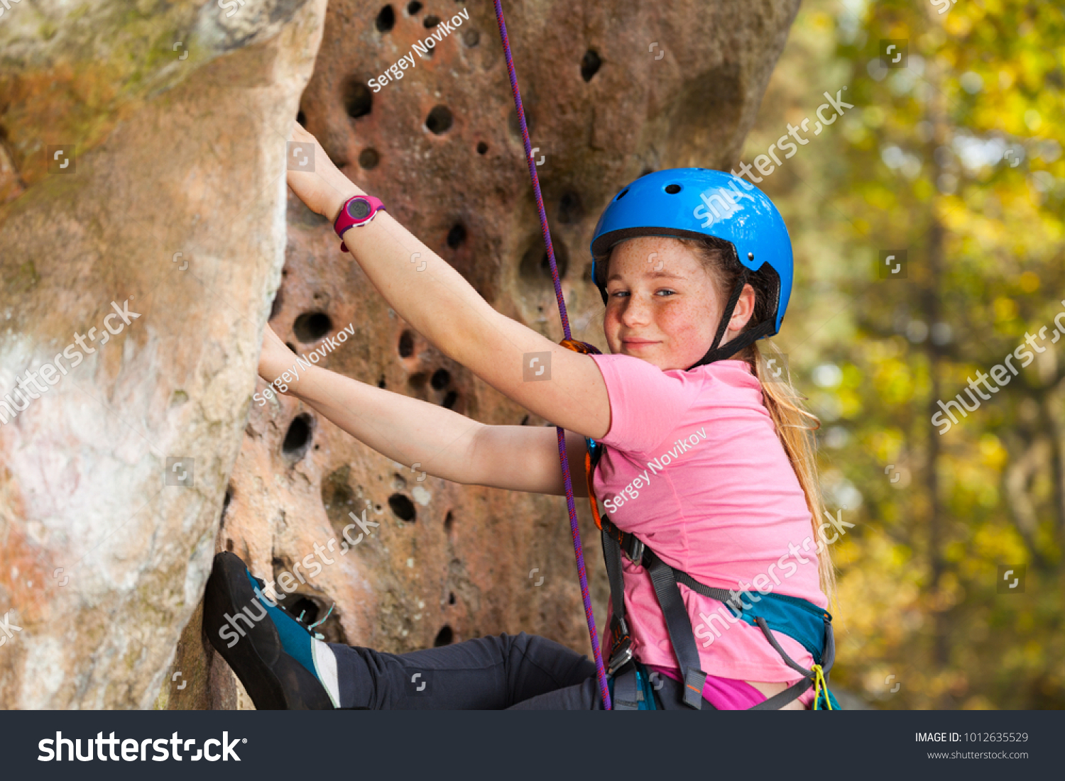 Girl in safety helmet climbing on the rock route #1012635529
