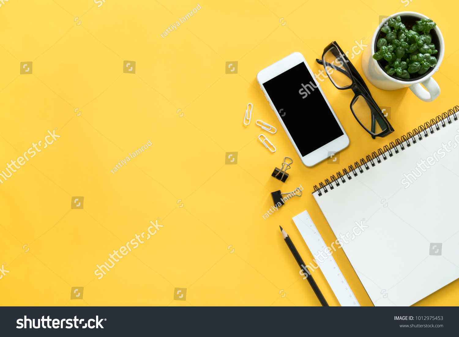 Mock up smartphone with office accessories on yellow background #1012975453