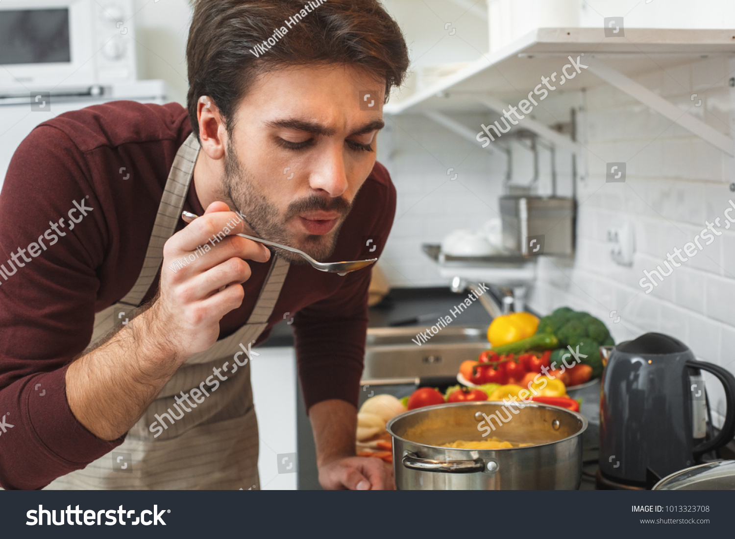 Young man cooking romantic dinner at home taste soup #1013323708