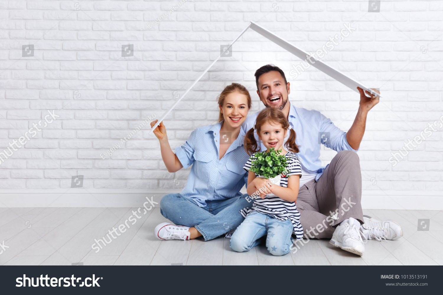concept housing a young family. Mother father and child in new house with a roof at empty brick wall
 #1013513191