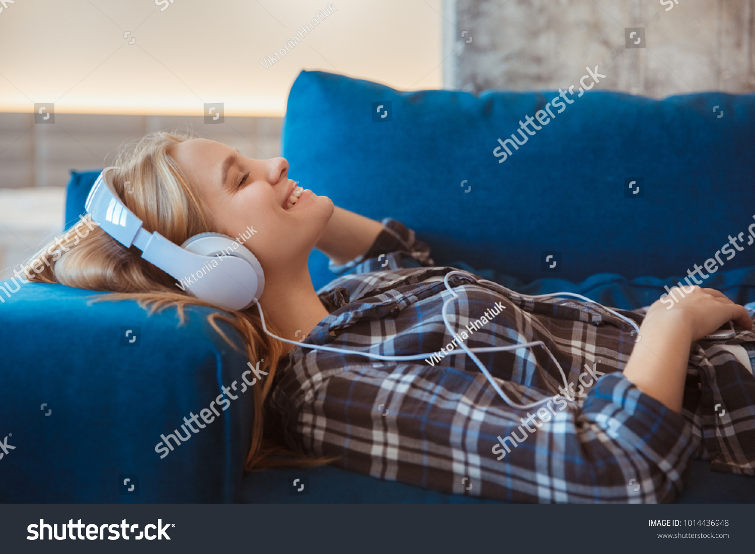 Young woman at home in the living room listening music smiling #1014436948