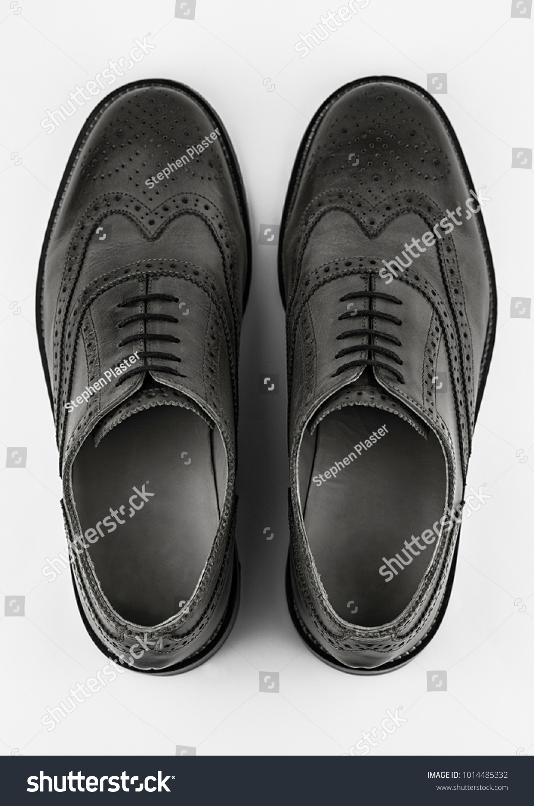 Pair of generic black brogue shoes shot from above on a white background. #1014485332