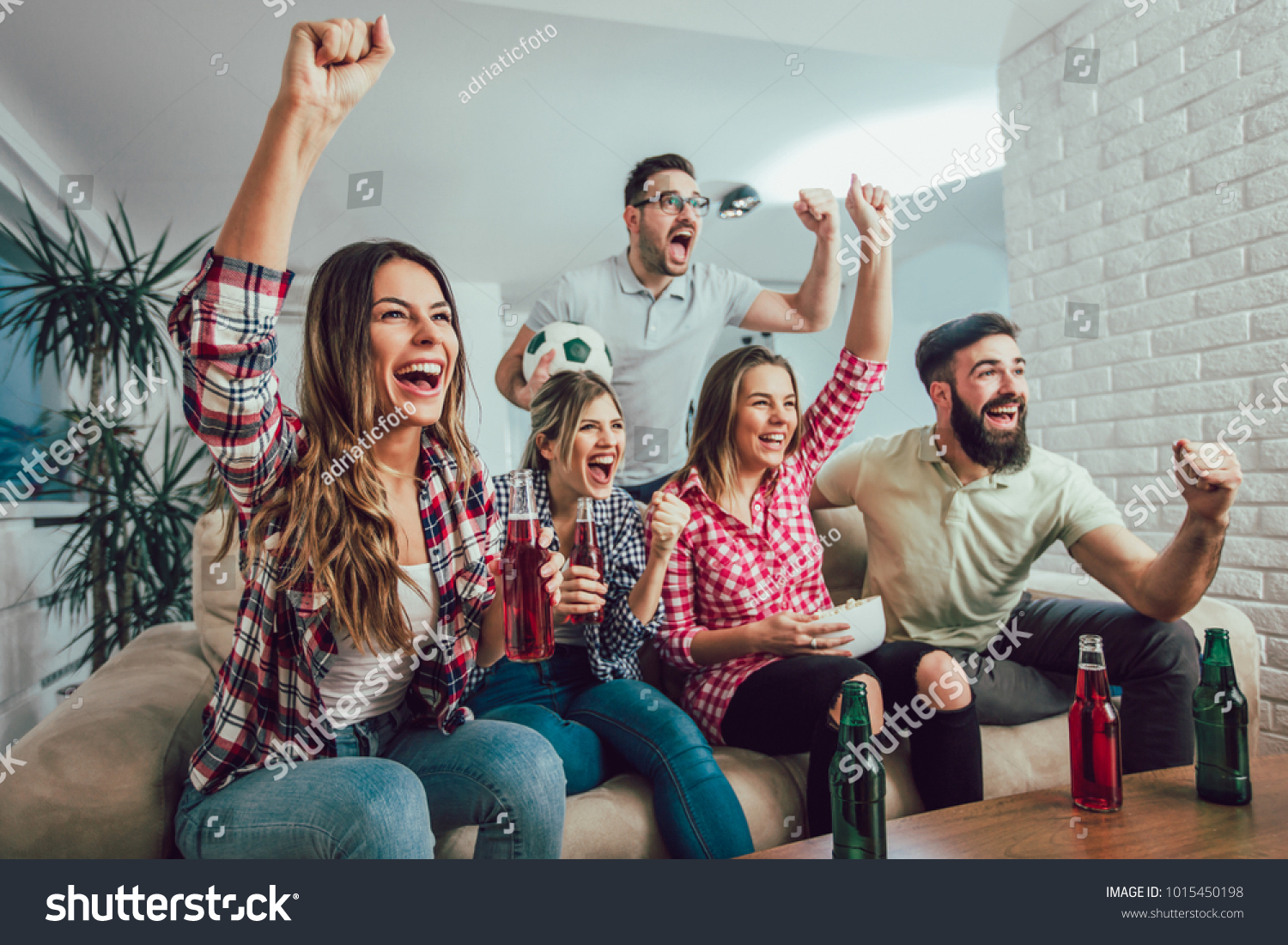 Happy friends or football fans watching soccer on tv and celebrating victory at home.Friendship, sports and entertainment concept. #1015450198