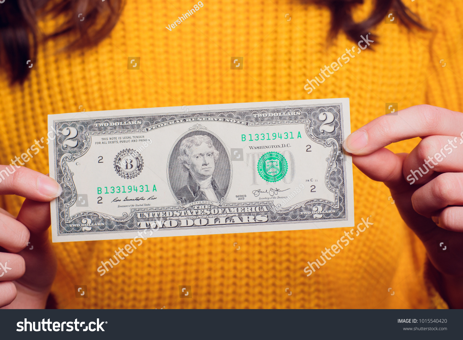 Hand two dollar bill. Isolated on a colored sweater. #1015540420