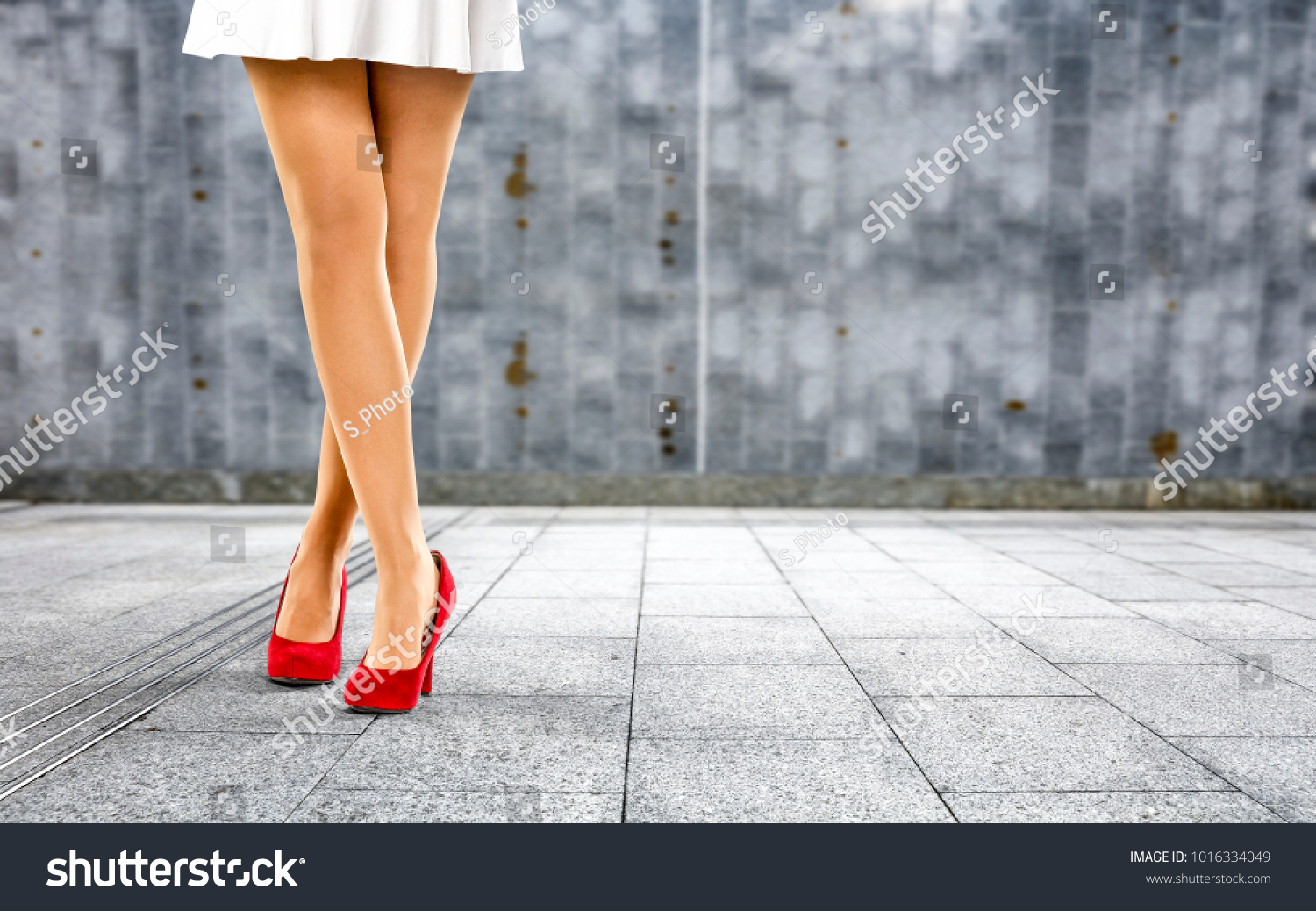 Woman legs with red shoes and wall of free space for your decoration.  #1016334049