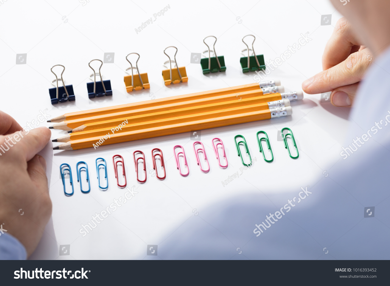 Businessman Arranging The Pencils In Between The Row Of Colorful Pins And Paper Clips #1016393452