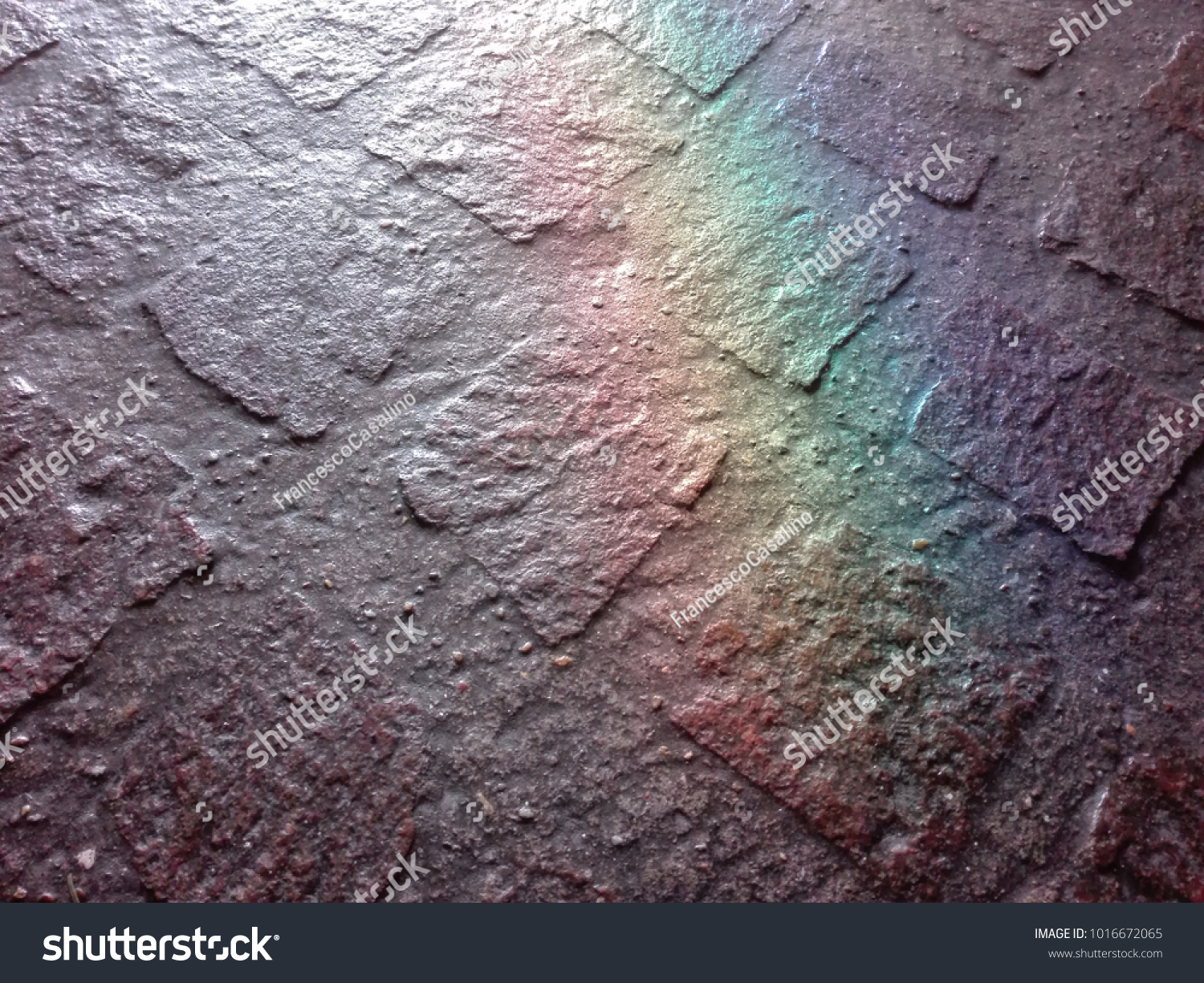 A stone floor lit by a window. A random reflection creates a rainbow on it. #1016672065