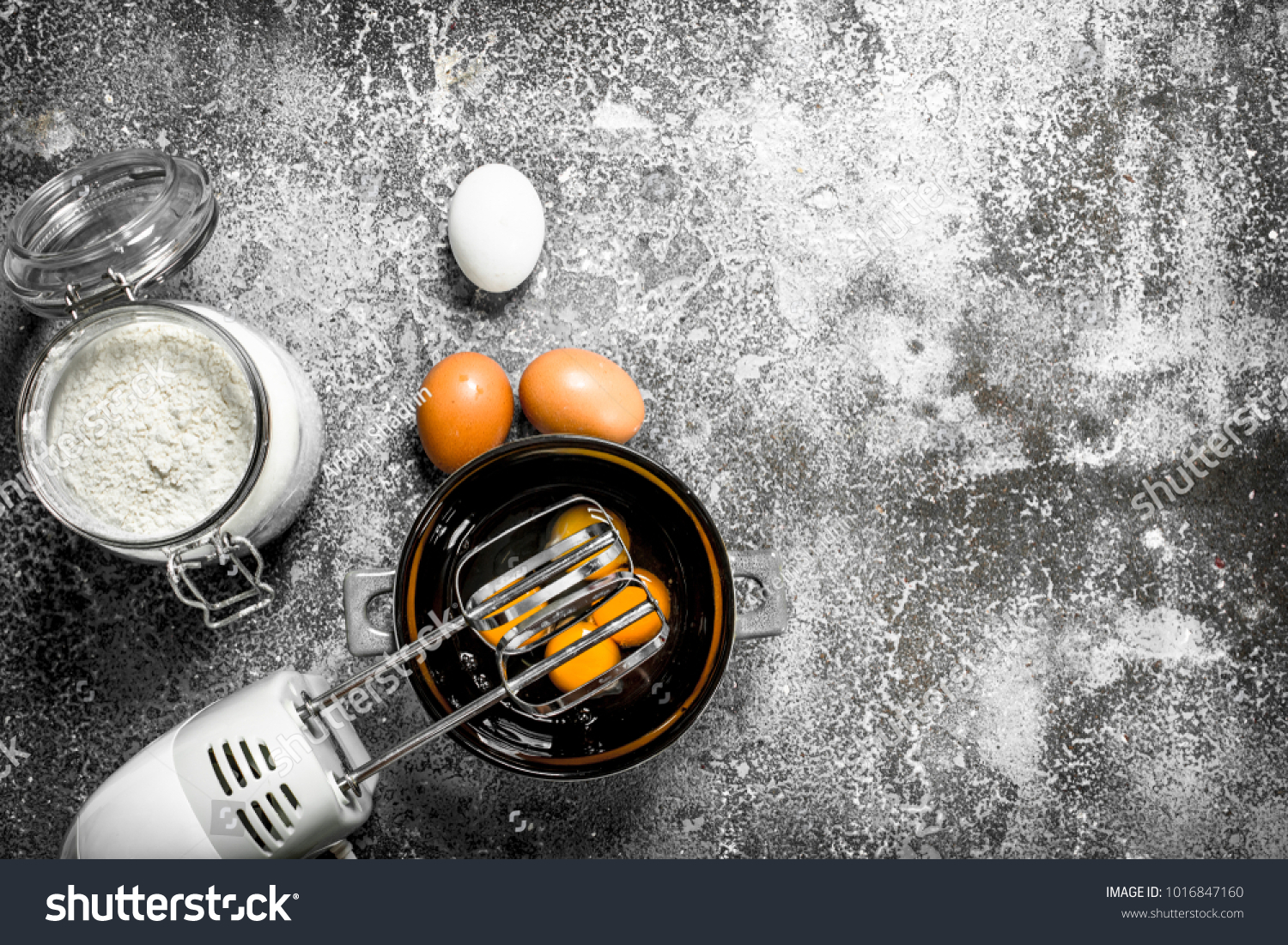 Baking background. Blend eggs with a mixer to make a dough. On a rustic background. #1016847160