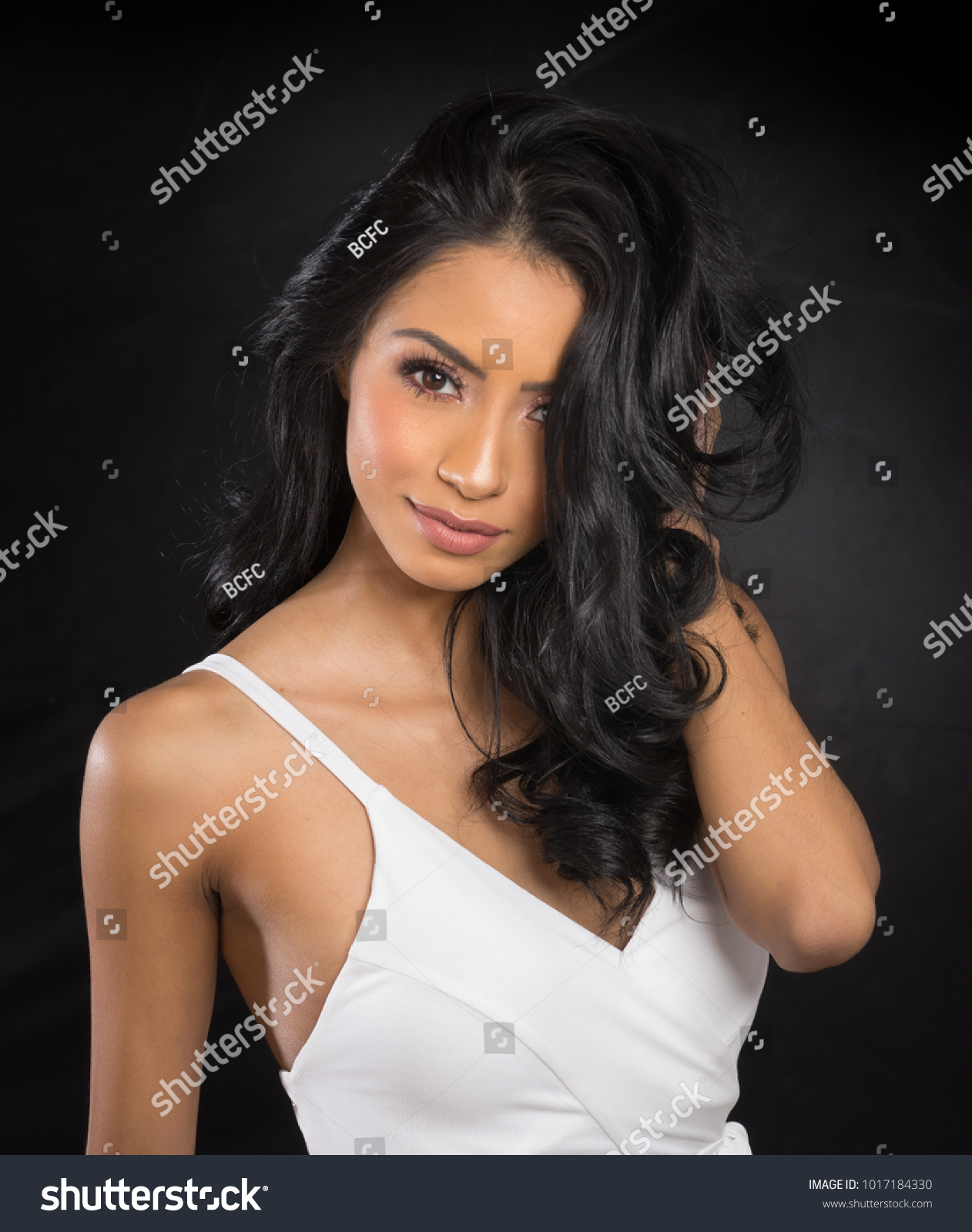 Beautiful woman's face and long dark hair wearing white dress #1017184330