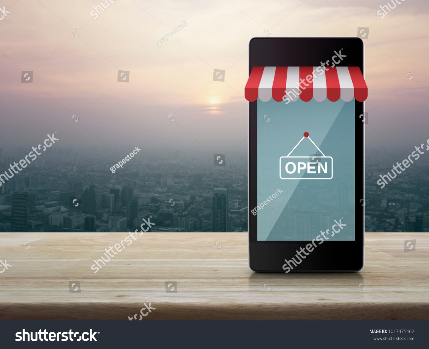 Modern smart mobile phone with on line shopping store graphic and open sign on wooden table over city tower at sunset, vintage style, Shop online concept #1017475462