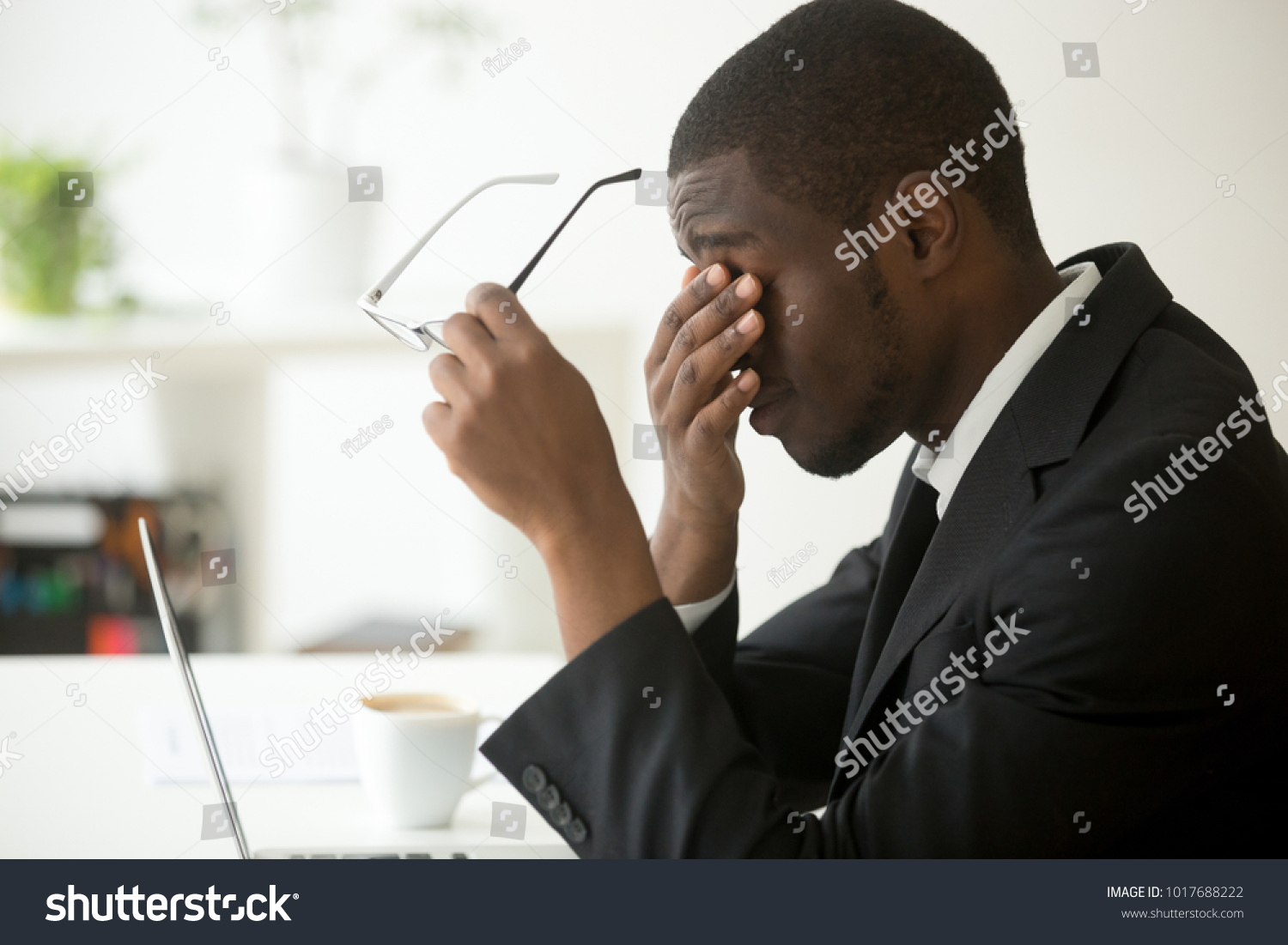 Tired of computer african businessman taking off glasses feels eye strain fatigue after long office work on laptop, exhausted overworked stressed depressed black man having bad sight vision problem #1017688222