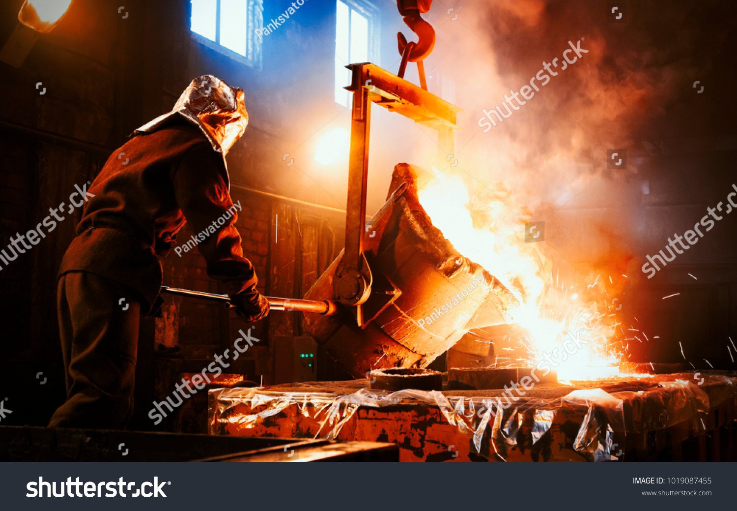 Workers operates at the metallurgical plant. The liquid metal is poured into molds. Worker controlling metal melting in furnaces. #1019087455