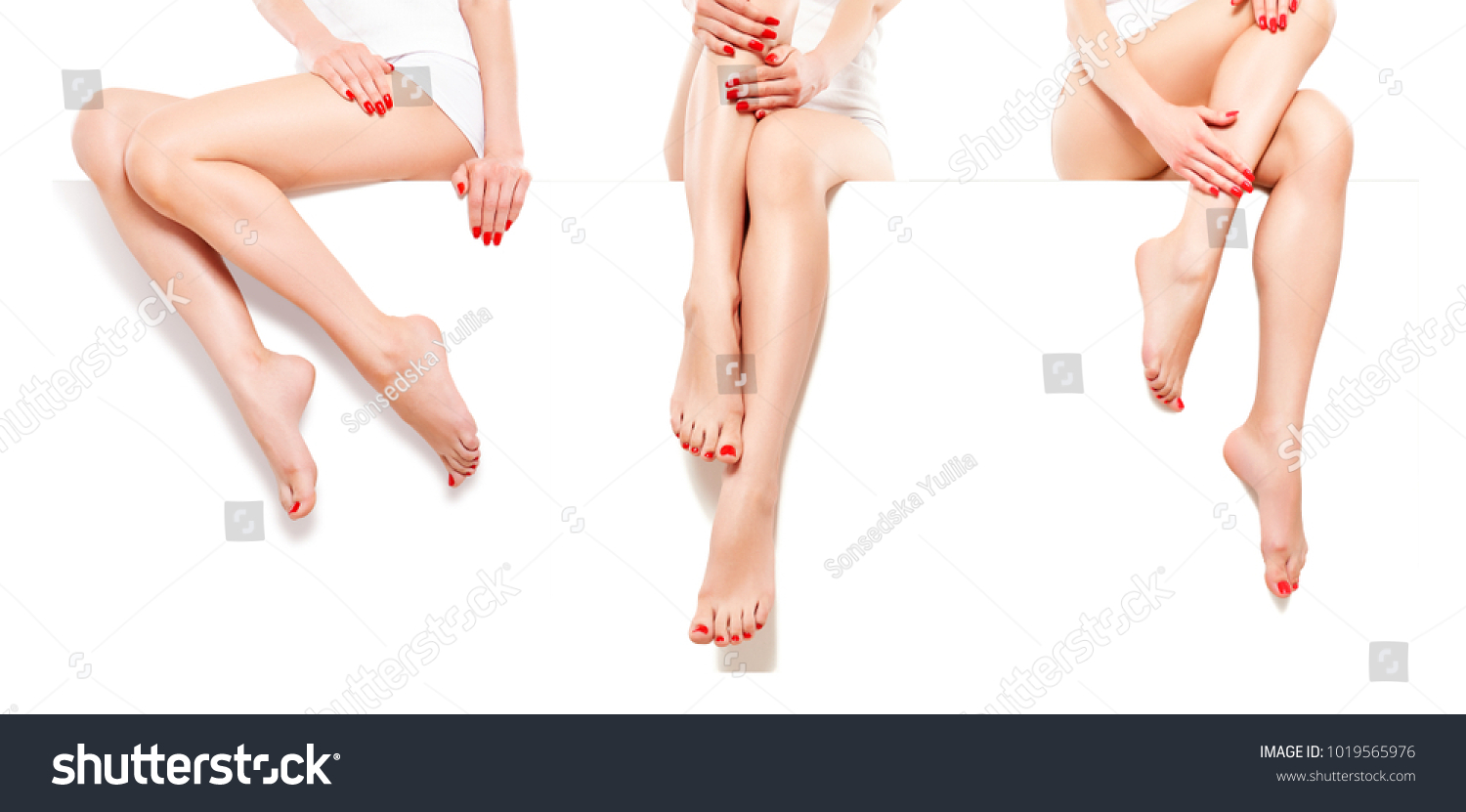 Three beautiful slim womans with red manicure, sitting at banner, isolated on white background #1019565976