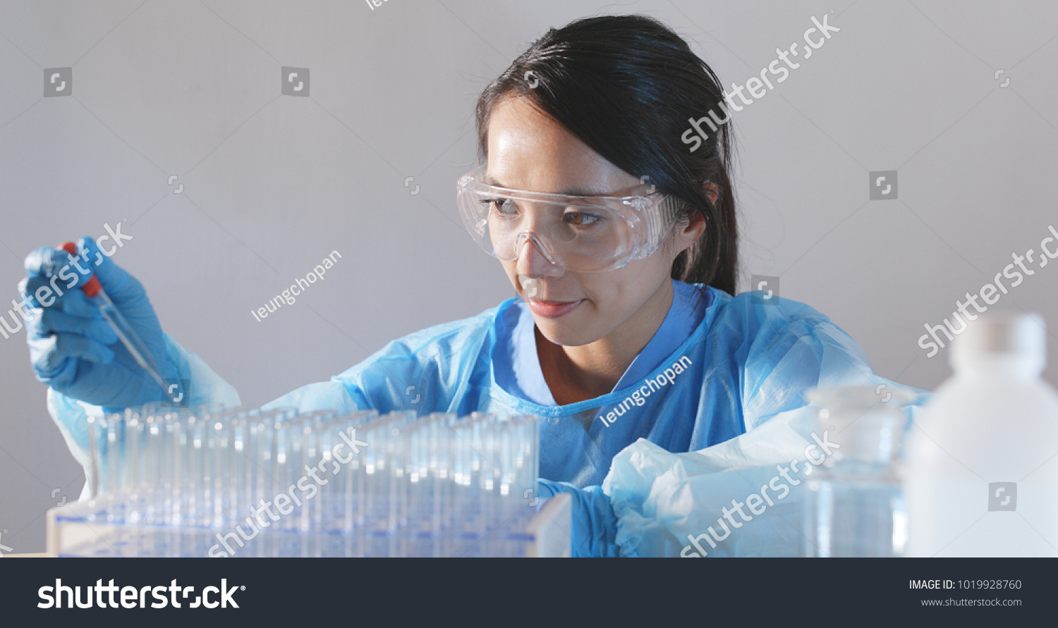 Female doctor analyzing liquid in test tube  #1019928760