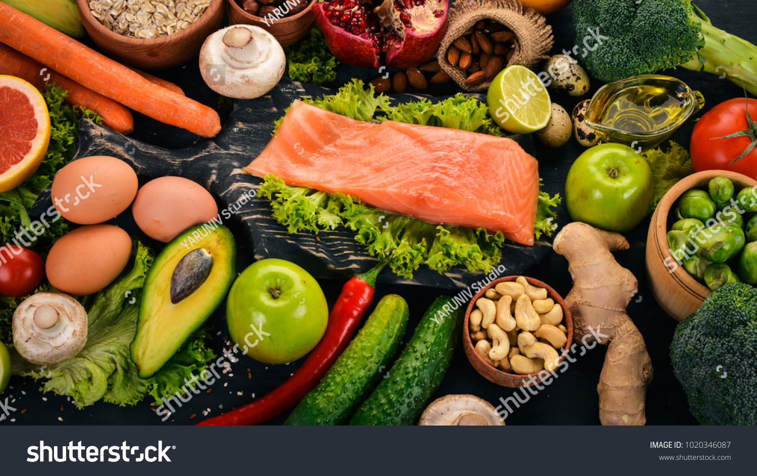 Healthy food. Fish salmon, avocado, broccoli, fresh vegetables, nuts and fruits. On a black background. Top view. Copy space. #1020346087
