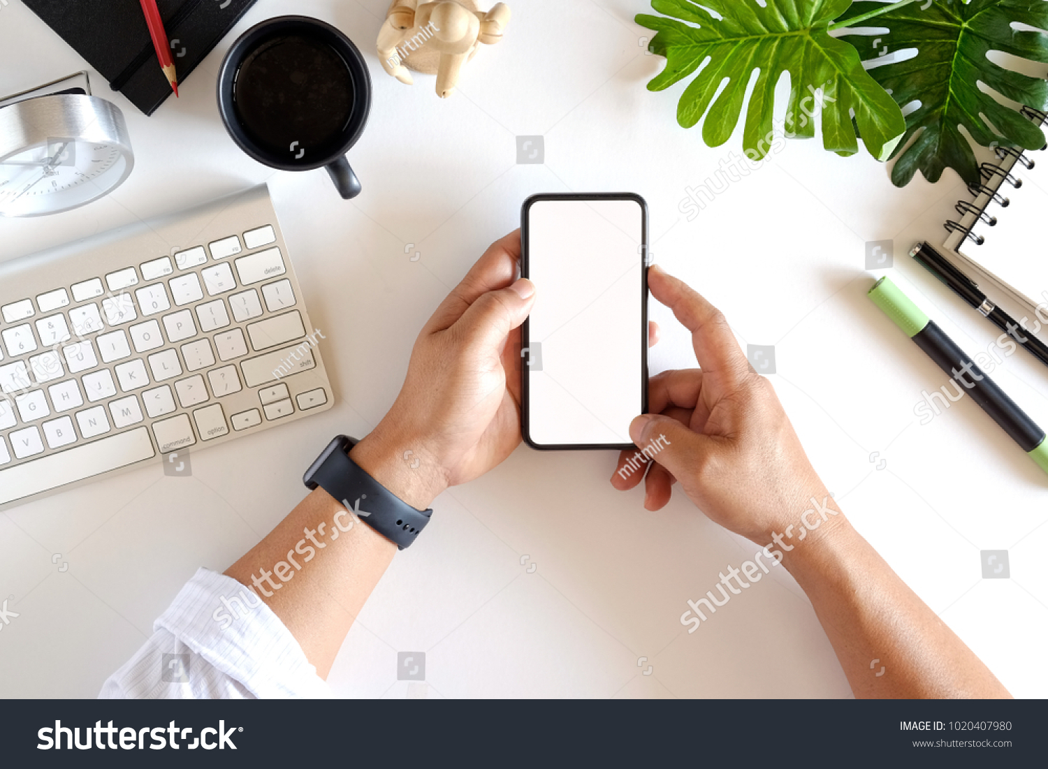 Cropped shot top view of businessman hands using smartphone mockup at the white office desk. Blank screen mobile phone for graphic display montage #1020407980