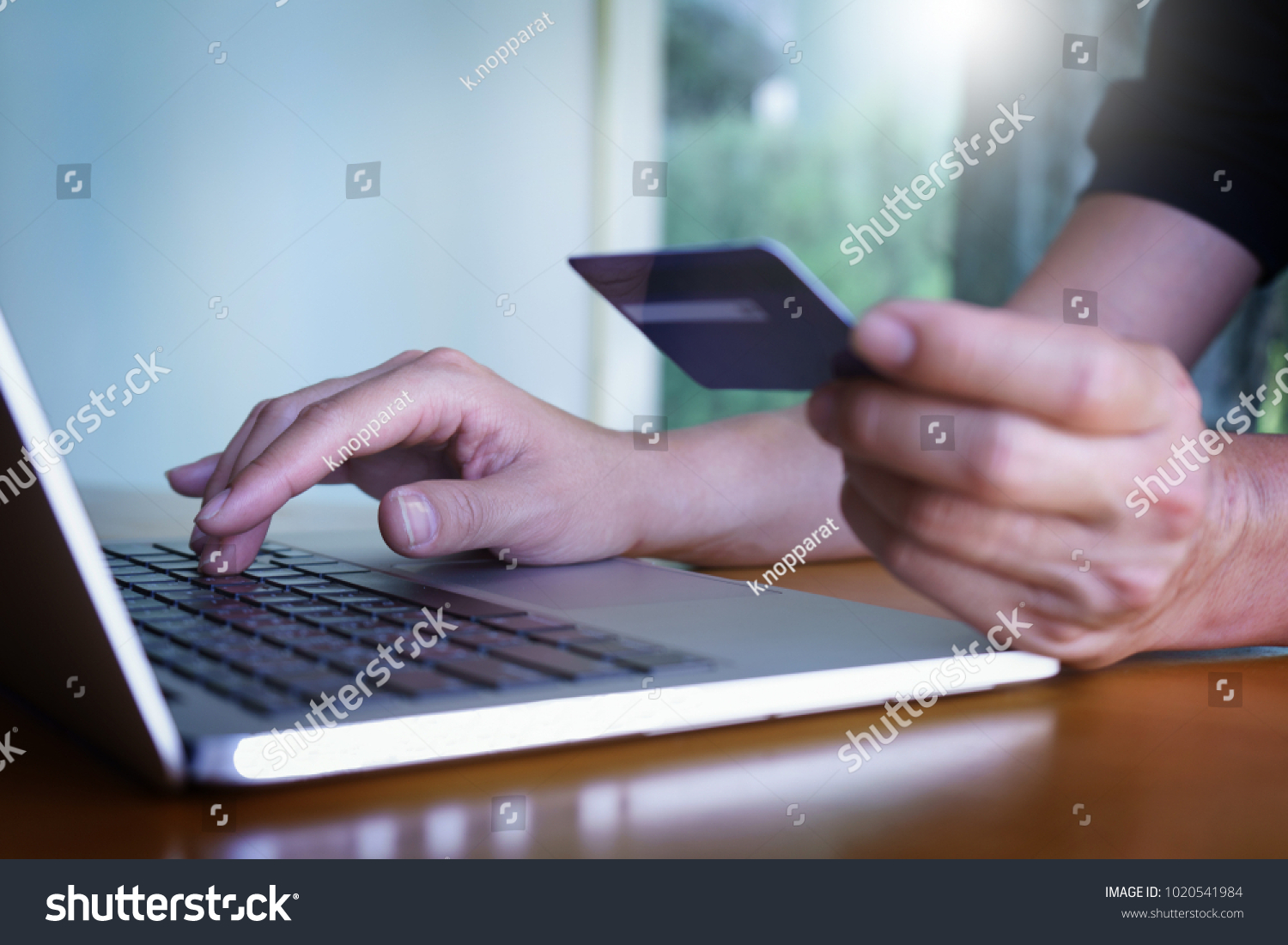 Man's hands holding credit card and typing on the keyboard of laptop, onine shopping, online payment. #1020541984