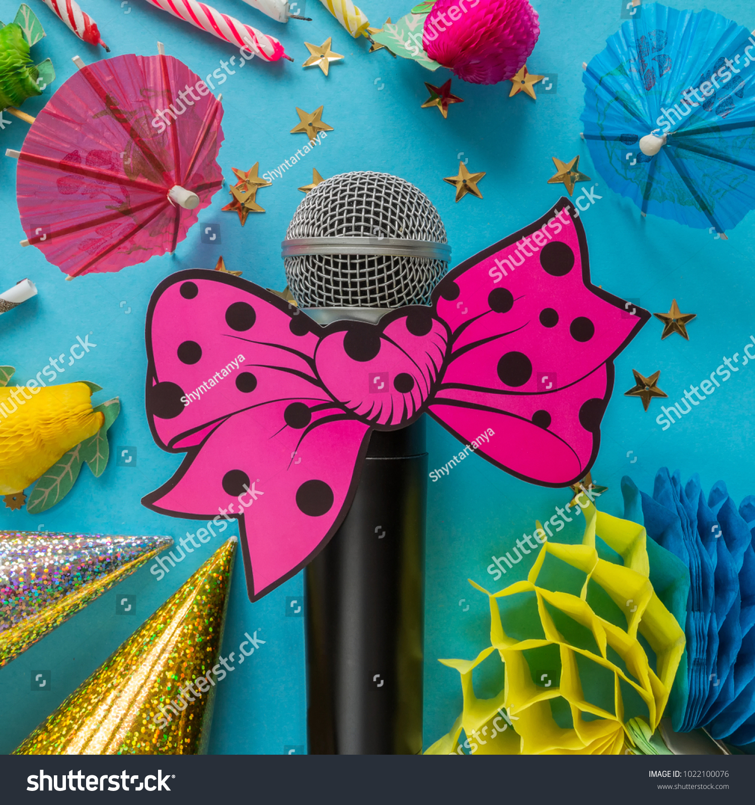 Birthday party with party hats microphone and streamers on a blue festive background with bright elements and with copy space, a concept of parties and karaoke #1022100076