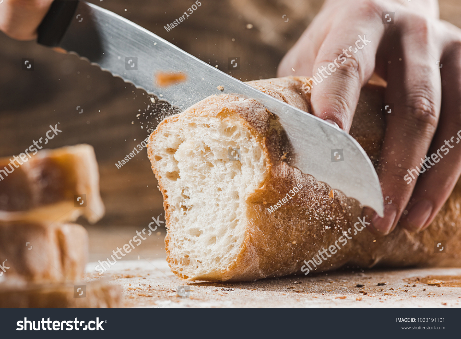 Whole grain bread put on kitchen wood plate with a chef holding gold knife for cut. Fresh bread on table close-up. Fresh bread on the kitchen table The healthy eating and traditional bakery concept #1023191101