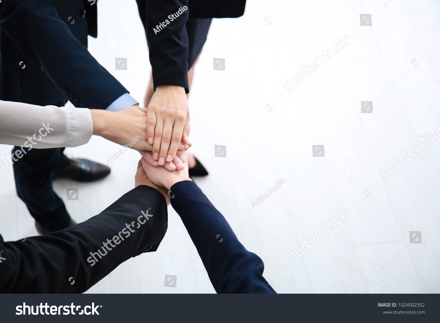 People putting hands together indoors. Unity concept #1024002352