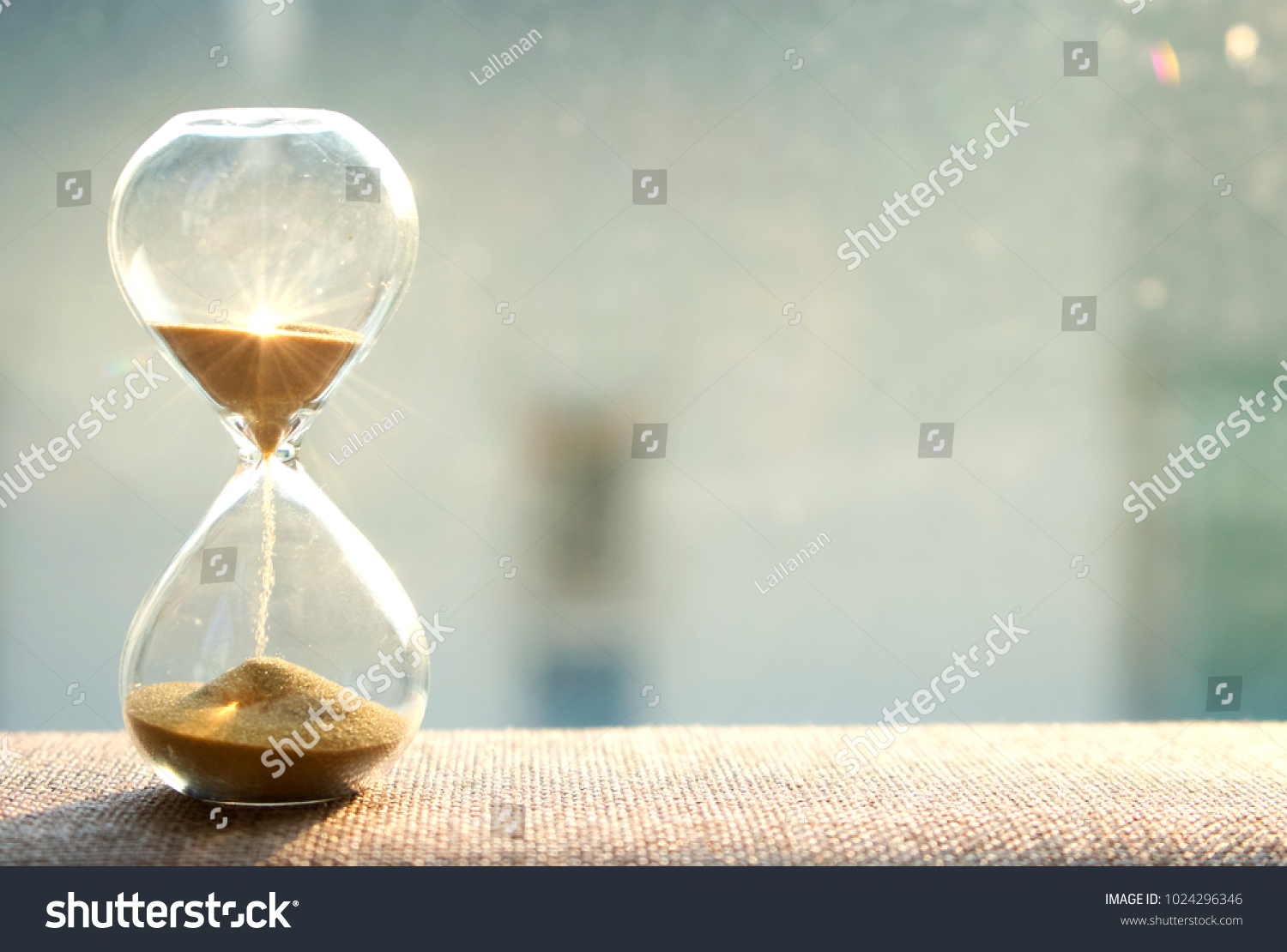 Life time passing concept. Hourglass with sun light background #1024296346