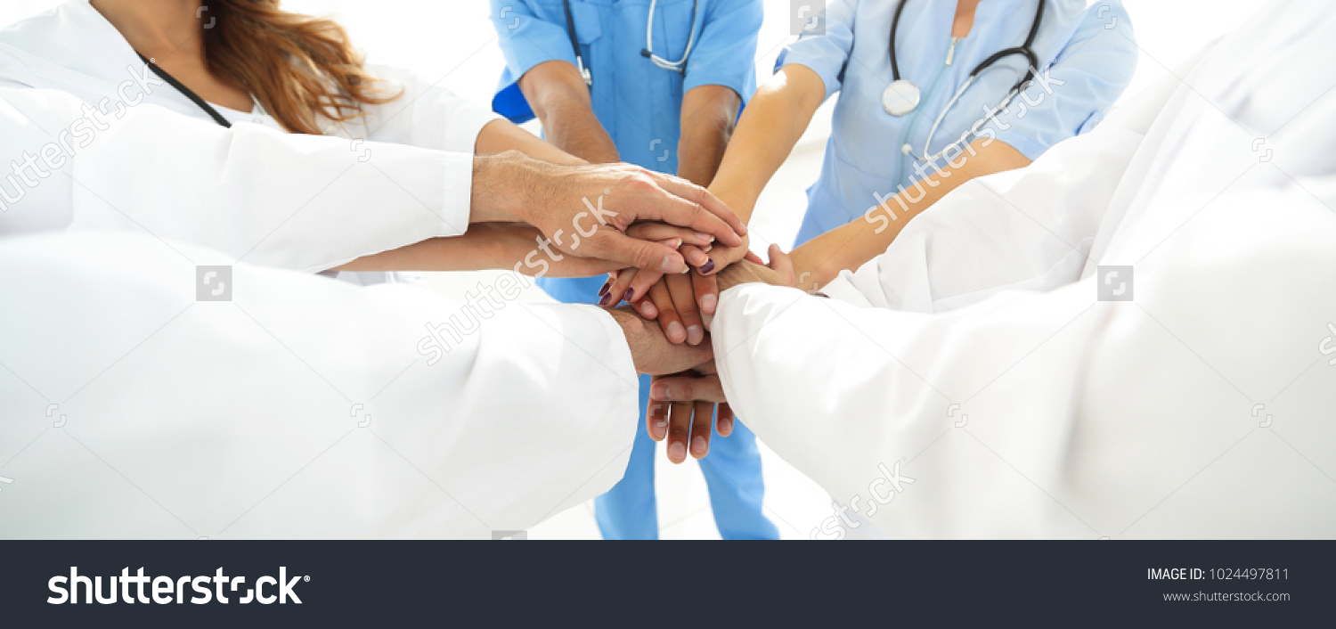 Doctors and nurses in a medical team stacking hands #1024497811