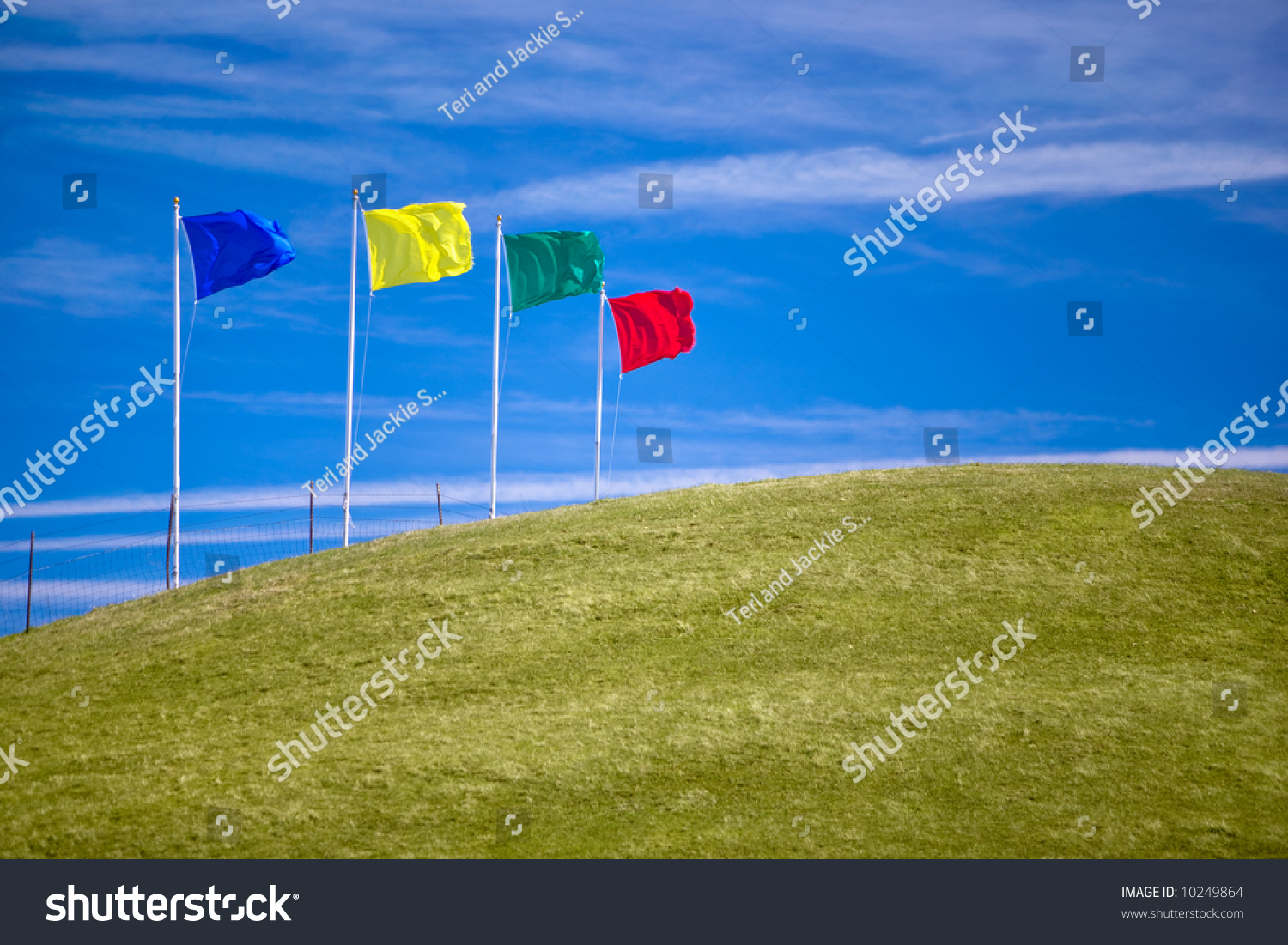 Four colorful flags on green grassy hill invite shoppers to attend an open house or other sales event.  Ample room for copy. #10249864