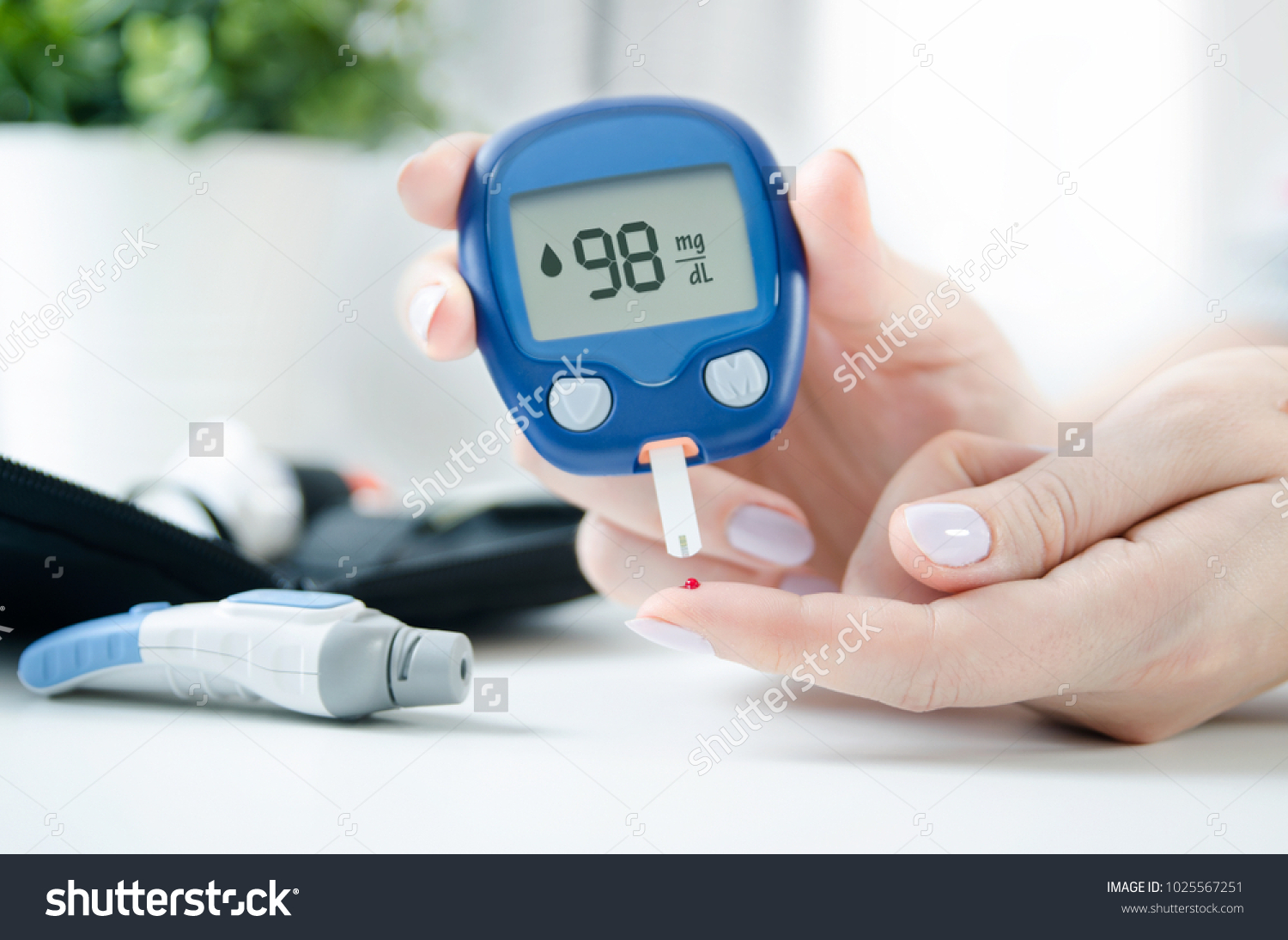 Diabetes checking blood sugar level. Woman using lancelet and glucometer at home. #1025567251