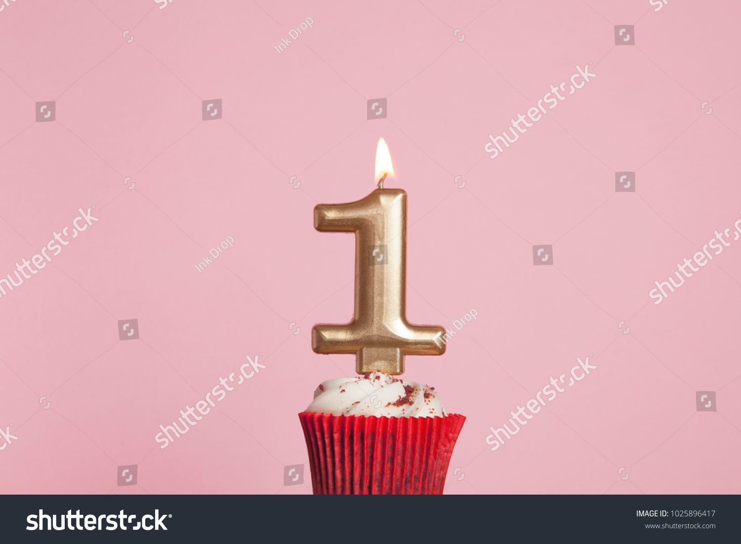 Number 1 gold candle in a cupcake against a pastel pink background #1025896417