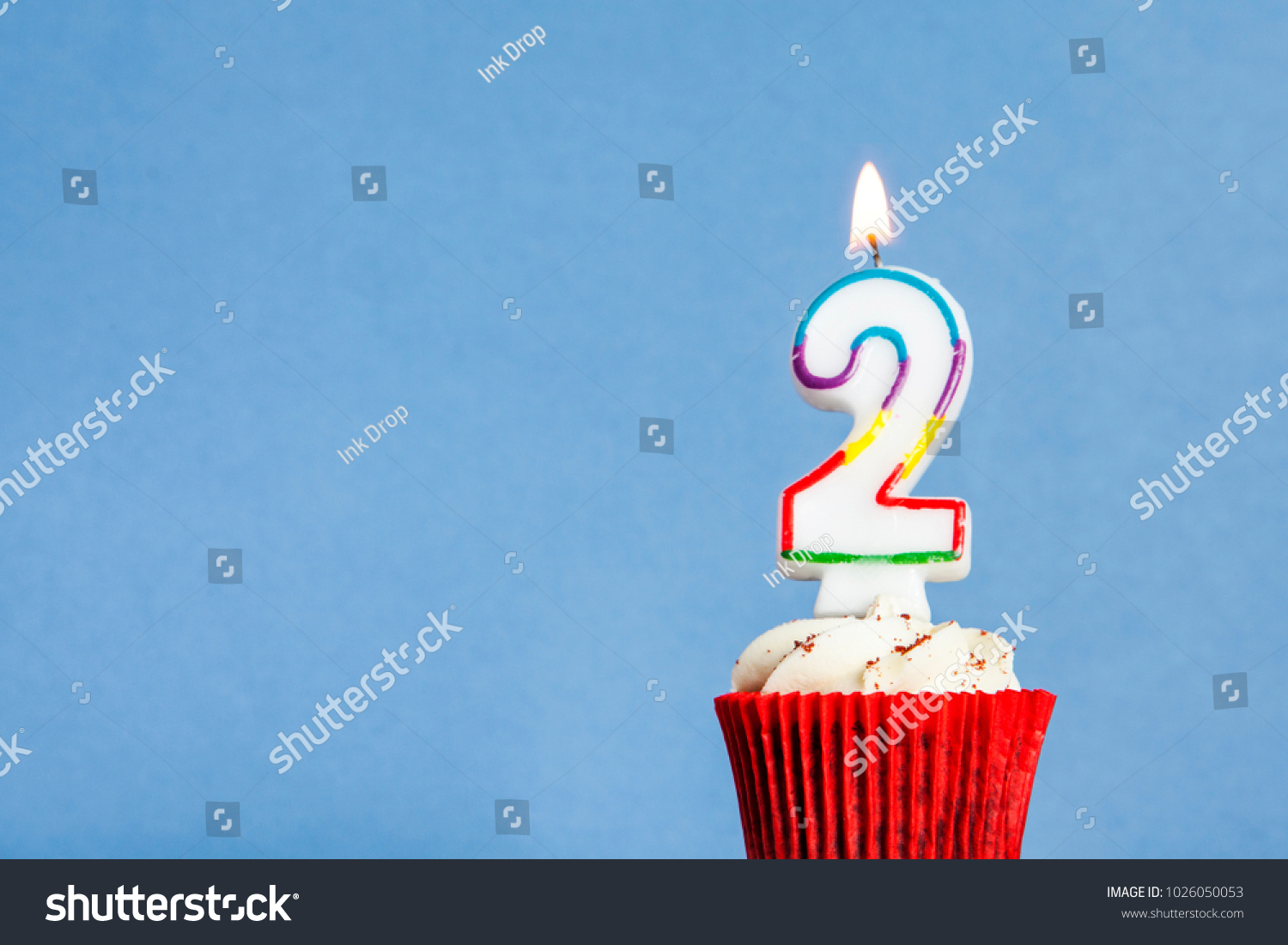 Number 2 birthday candle in a cupcake against a blue background #1026050053