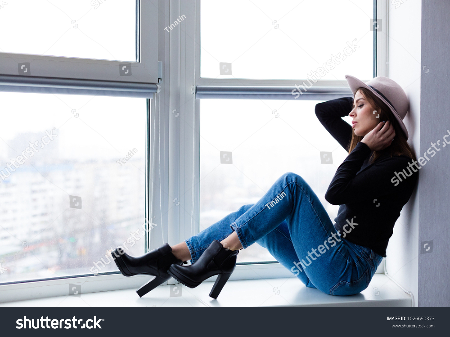 Beautiful boho woman in wool hat sitting by the window #1026690373