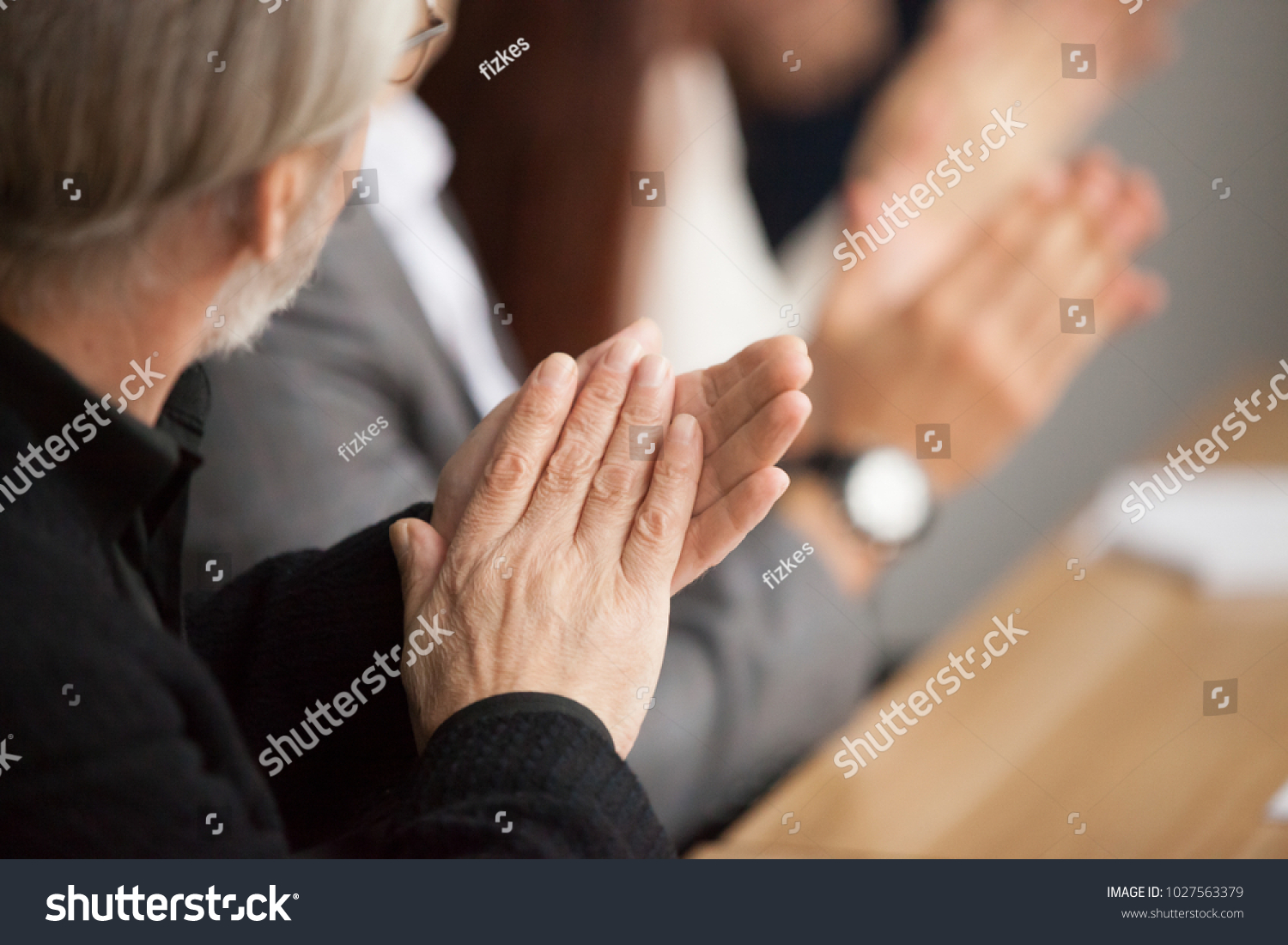 Senior gray-haired businessman clapping hands attending conference, aged training participant applauding at group meeting, old man expressing appreciation or congratulation, rear view, focus on hands #1027563379